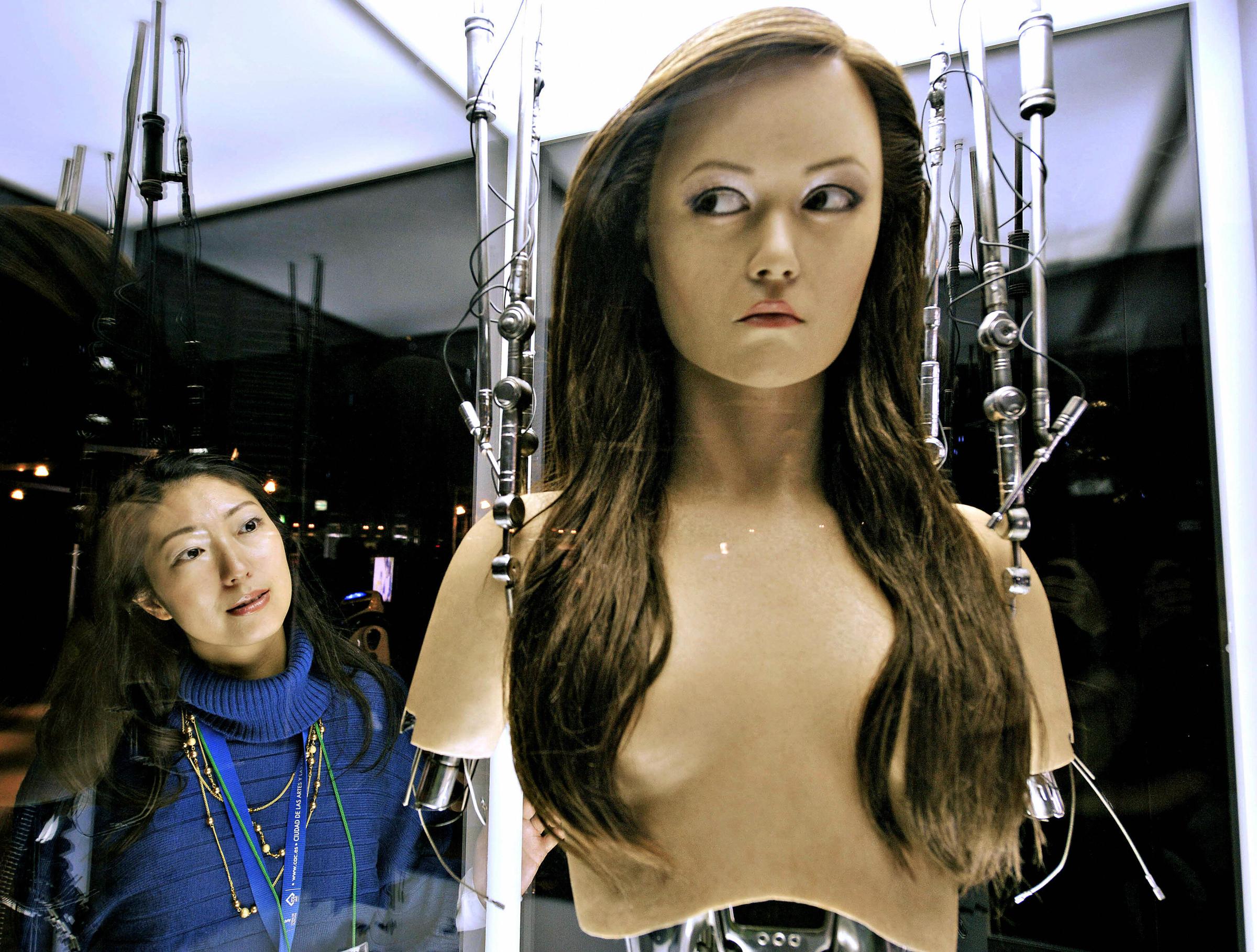 A woman watches a full-scale figure of a terminator robot "Cameron Phillipes" at a preview of the Terminator Exhibition in Tokyo on March 18, 2009.