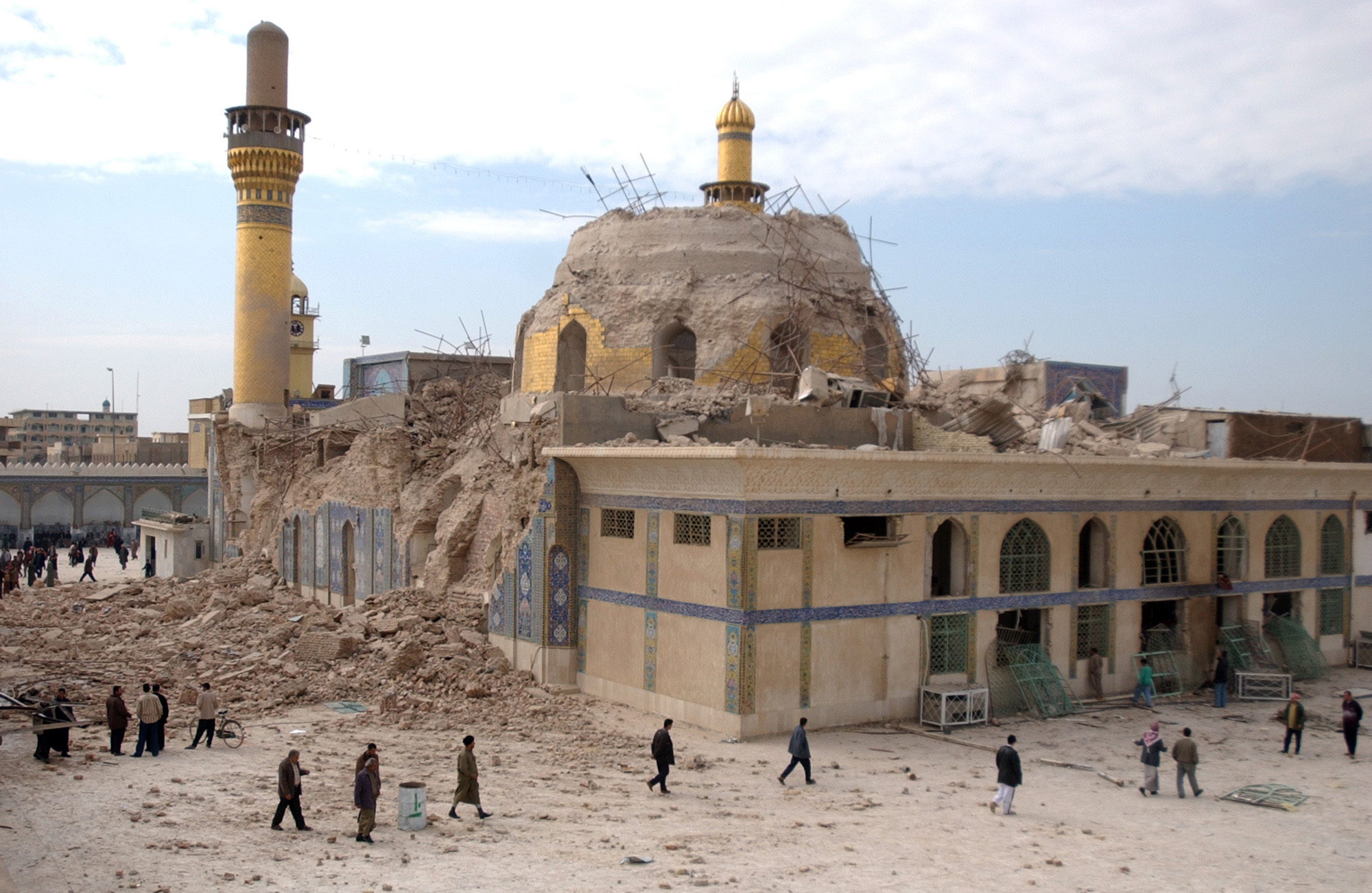 Iraqis walk past the damaged al-Askari mosque following an explosion in Samarra, 95 kilometers (60 miles) north of Baghdad, Iraq on Feb. 22, 2006. (Hameed Rasheed—AP)