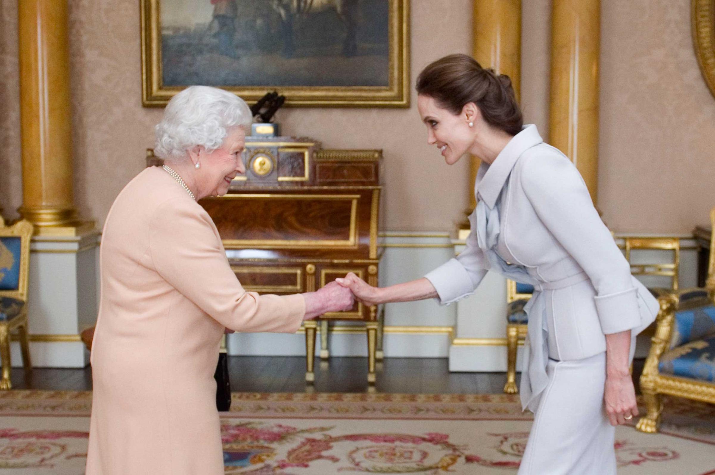 Actress Angelina Jolie, right, is presented with the Insignia of an Honorary Dame Grand Cross of the Most Distinguished Order of St Michael and St George by Britain's Queen Elizabeth II at Buckingham Palace, London, Oct. 10, 2014.