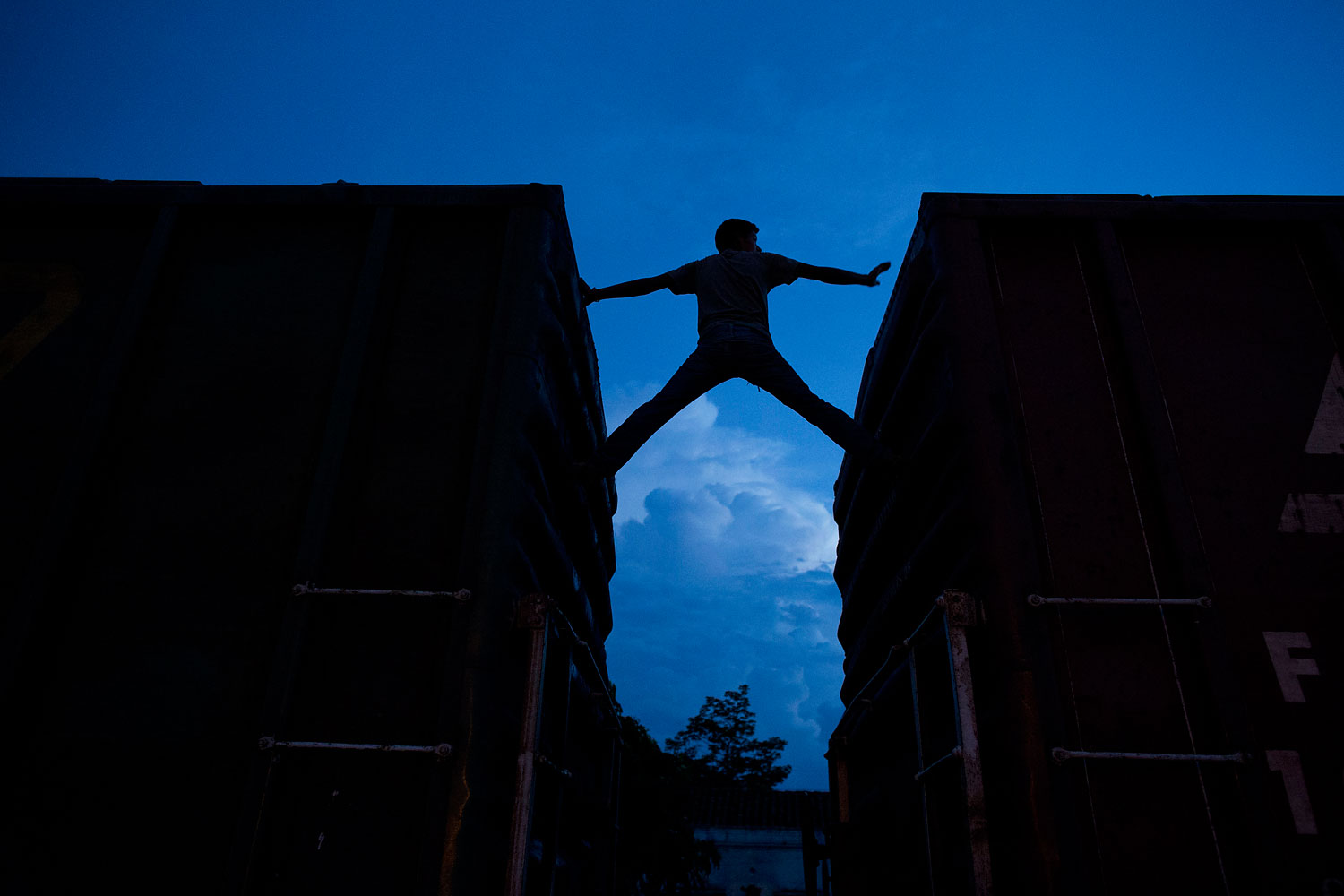 A Central American migrant practices scaling parked boxcars as he awaits the arrival of a northbound freight train in Arriaga, Mexico, on June 19, 2014.