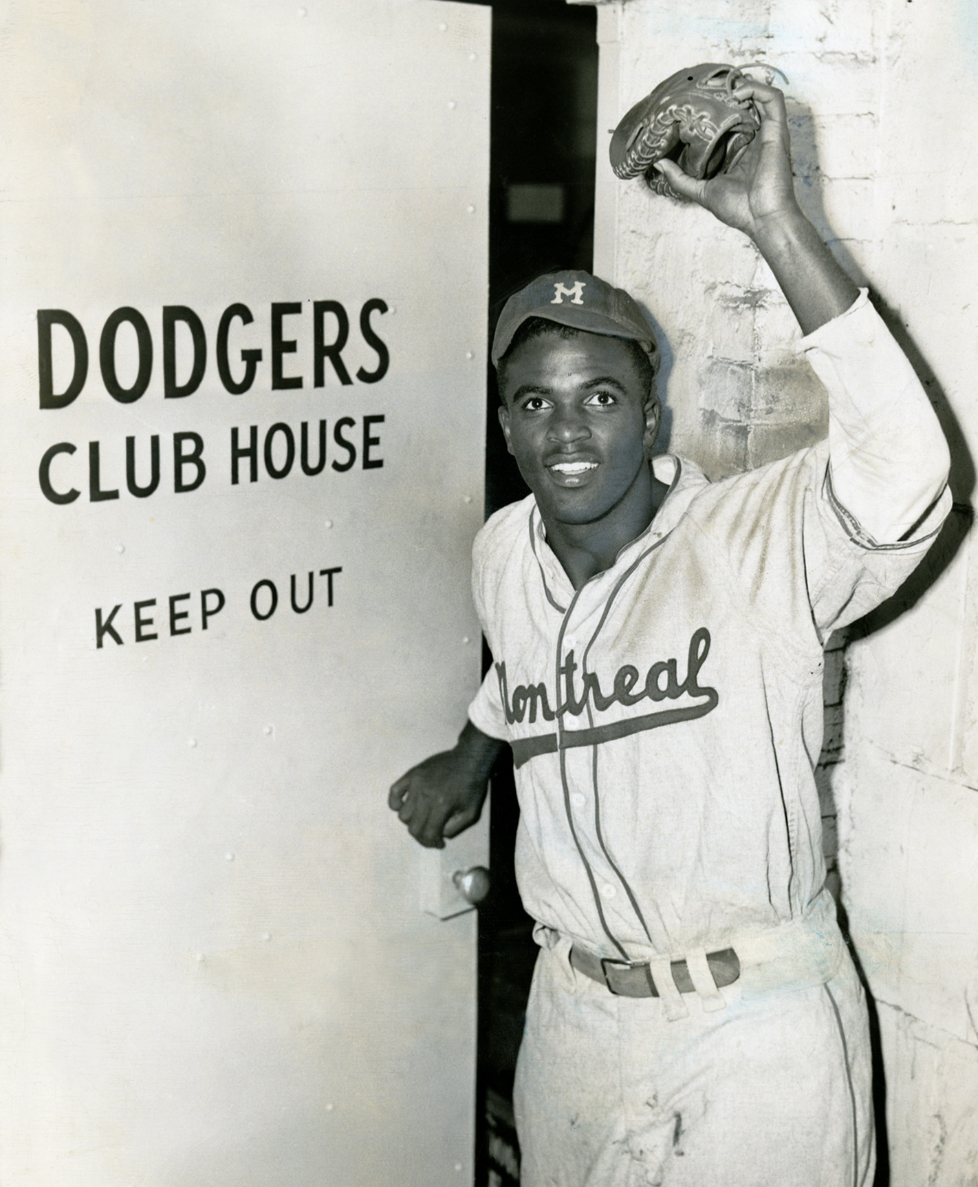 Jackie Robinson opens the door to the Dodgers' clubhouse on the day Brooklyn purchased his contract, making him the first African-American player in modern baseball history to join a major league club, New York City, April 10, 1947.