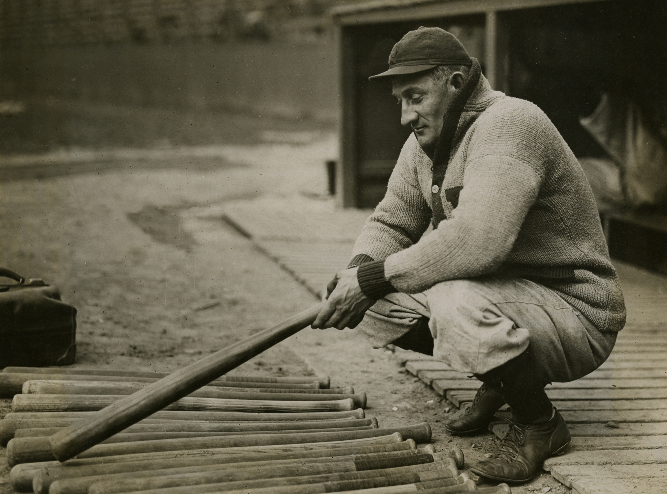 Pittsburgh great Honus Wagner selects a bat in front of the Pirates dugout, 1915.