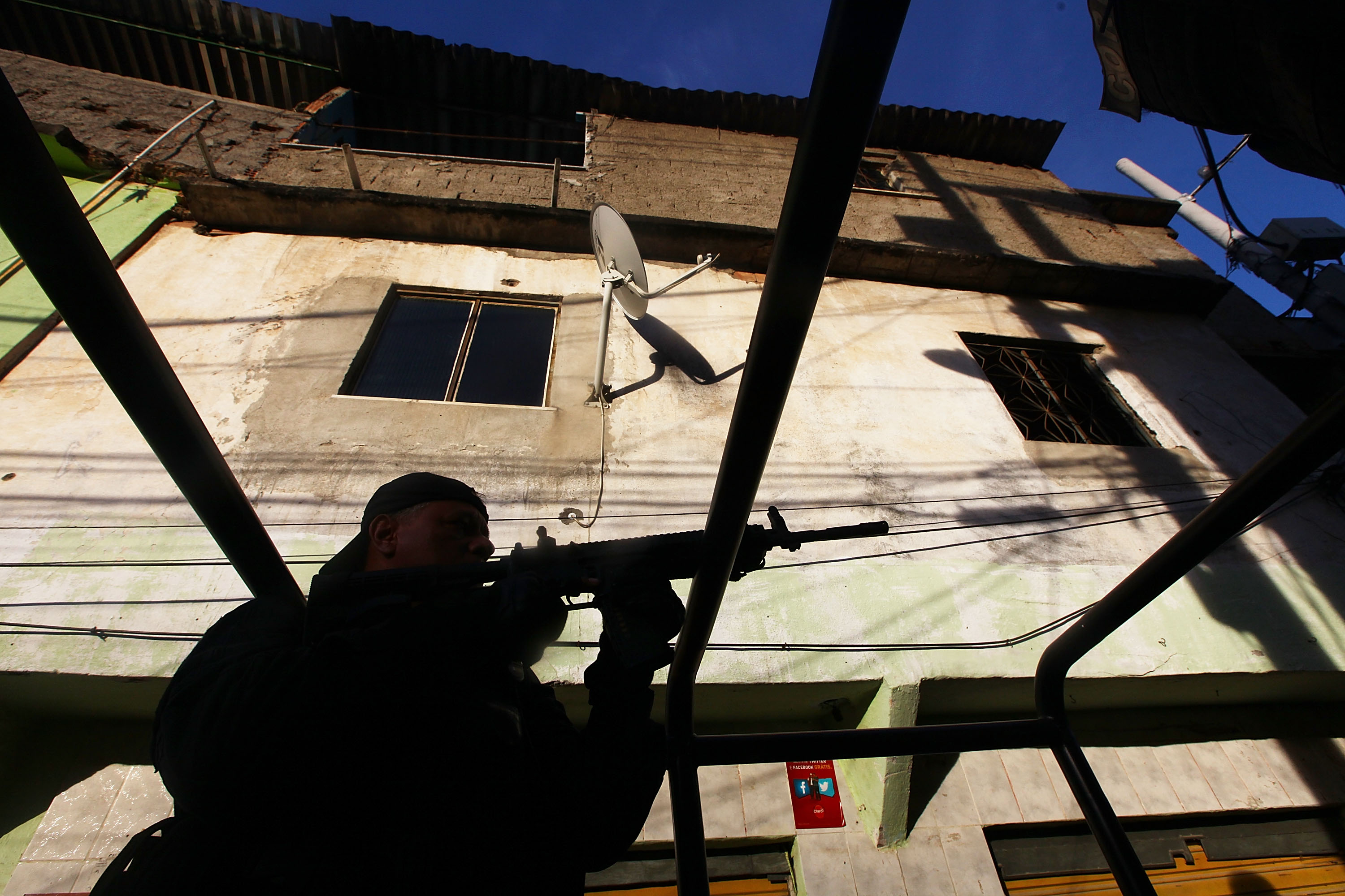 Squad commander Inspector Julio Goncalves from the CORE police special forces aims his weapon during an operation to search of fugitives in the Complexo do Alemao pacified favela on May 13, 2014 in Rio de Janeiro.