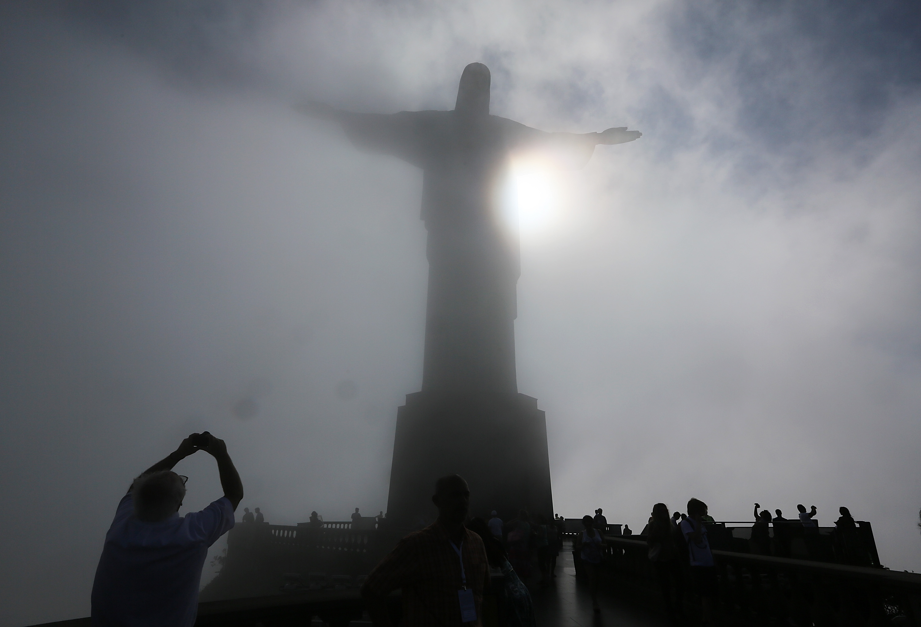 People gather beneath the Christ the Redeemer statue as mist passes at the summit of Corcovado on October 22, 2013 in Rio de Janeiro.