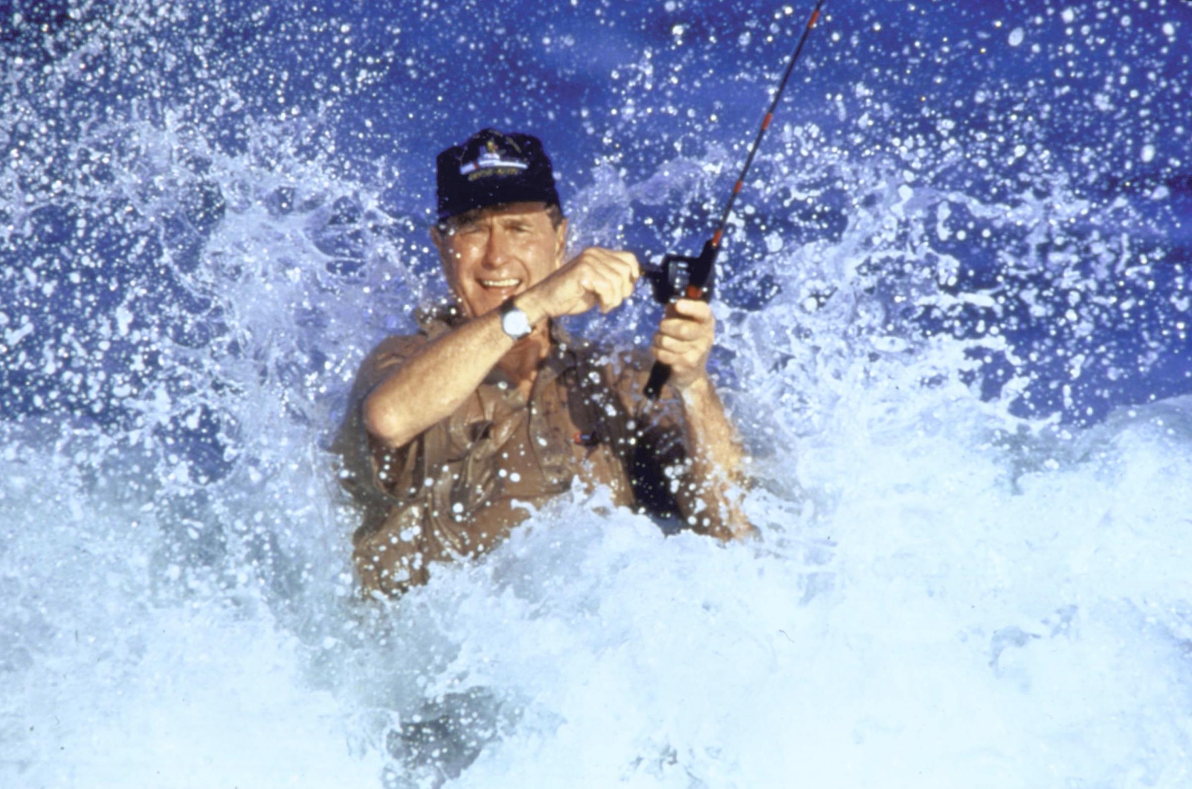President elect George H.W. Bush casting a fishing rod with surf splashing around him on January 1, 1988.