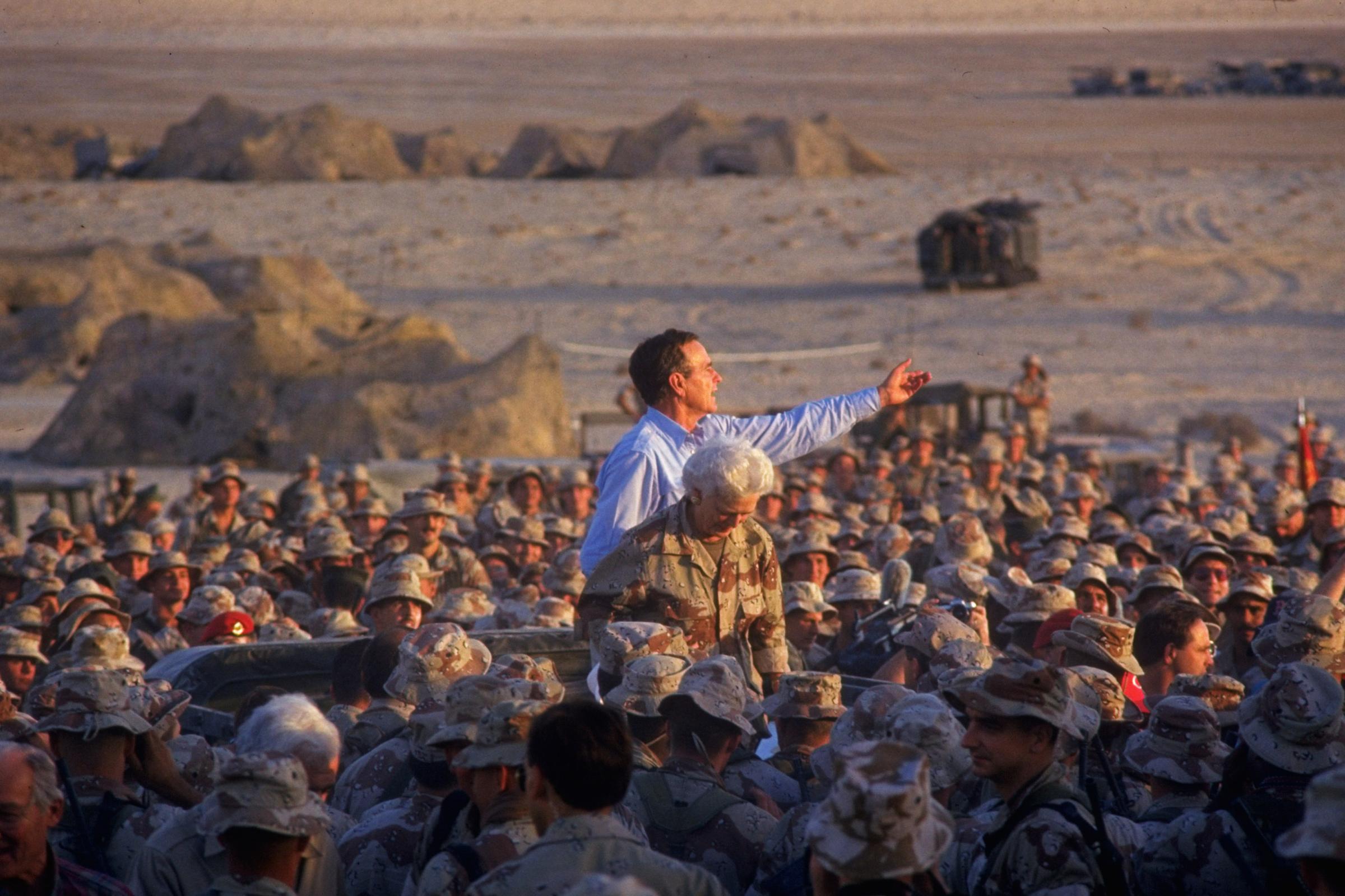 President George H.W. Bush and Barbara Bush poised above a crowd of First Marine Division Desert Command Post marines on thanksgiving during the Gulf Crisis on November 22, 1990.