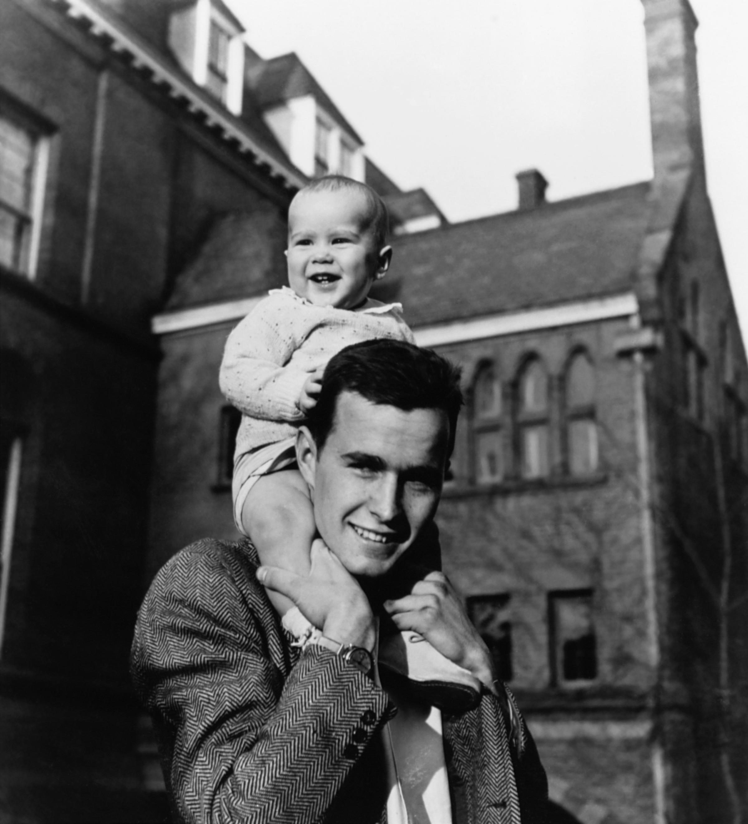 George H.W. Bush carries his infant son George W. Bush on his shoulders at Yale University in New Haven, Conn.