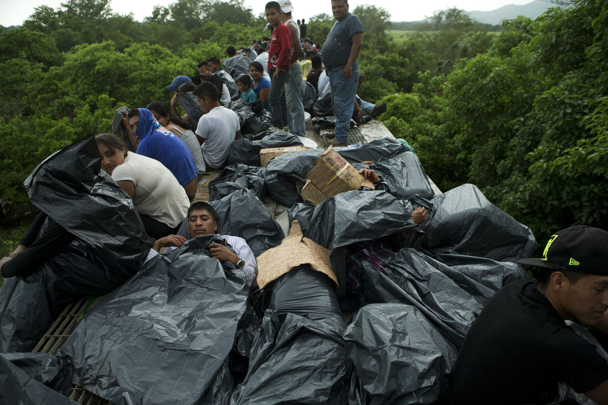 Central American migrants use trash bags and cardboard to protect themselves from the rain as they wait atop a stuck freight train, outside Reforma de Pineda, Chiapas state, Mexico, June 20, 2014.