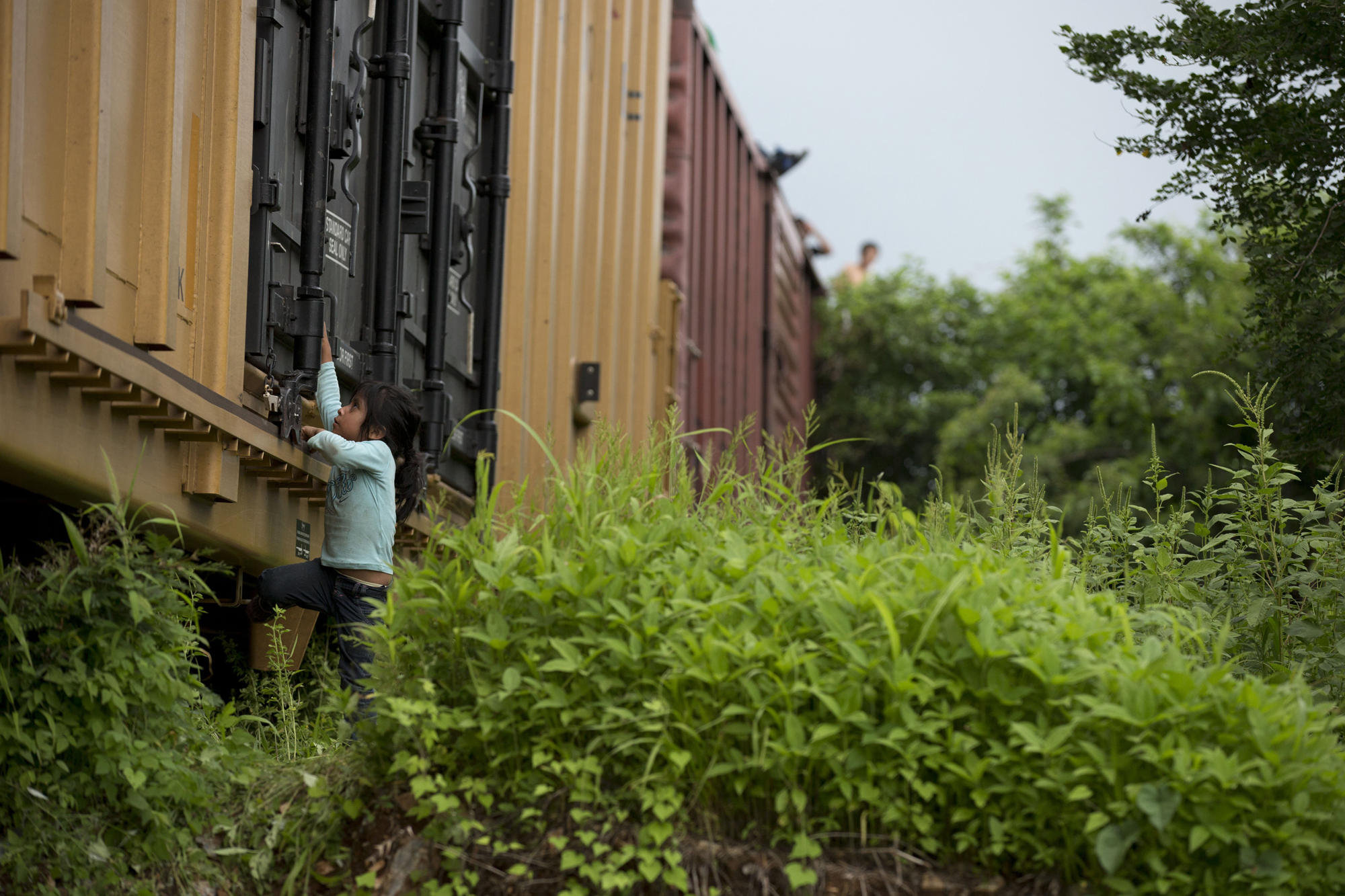 A young girl traveling with Central American migrants plays on the freight train they had been riding, after it suffered a minor derailment in a remote wooded area outside Reforma de Pineda, Mexico, June 20.