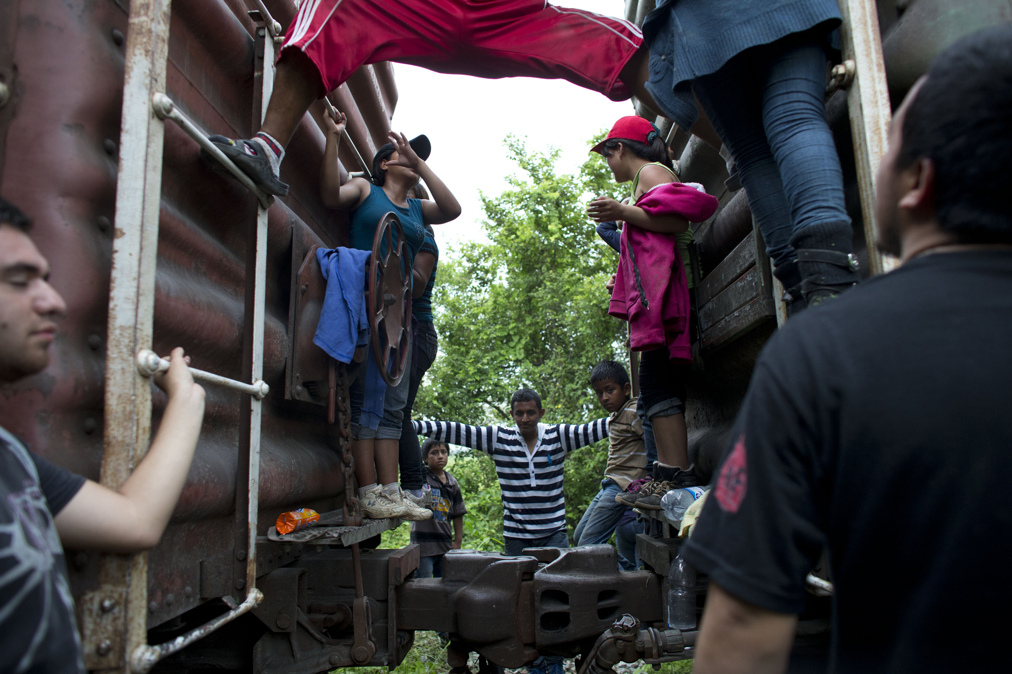 Central American migrants hang out around the northbound freight train they had been traveling on, after it suffered a minor derailment in a remote wooded area outside Reforma de Pineda, Mexico, June 20.