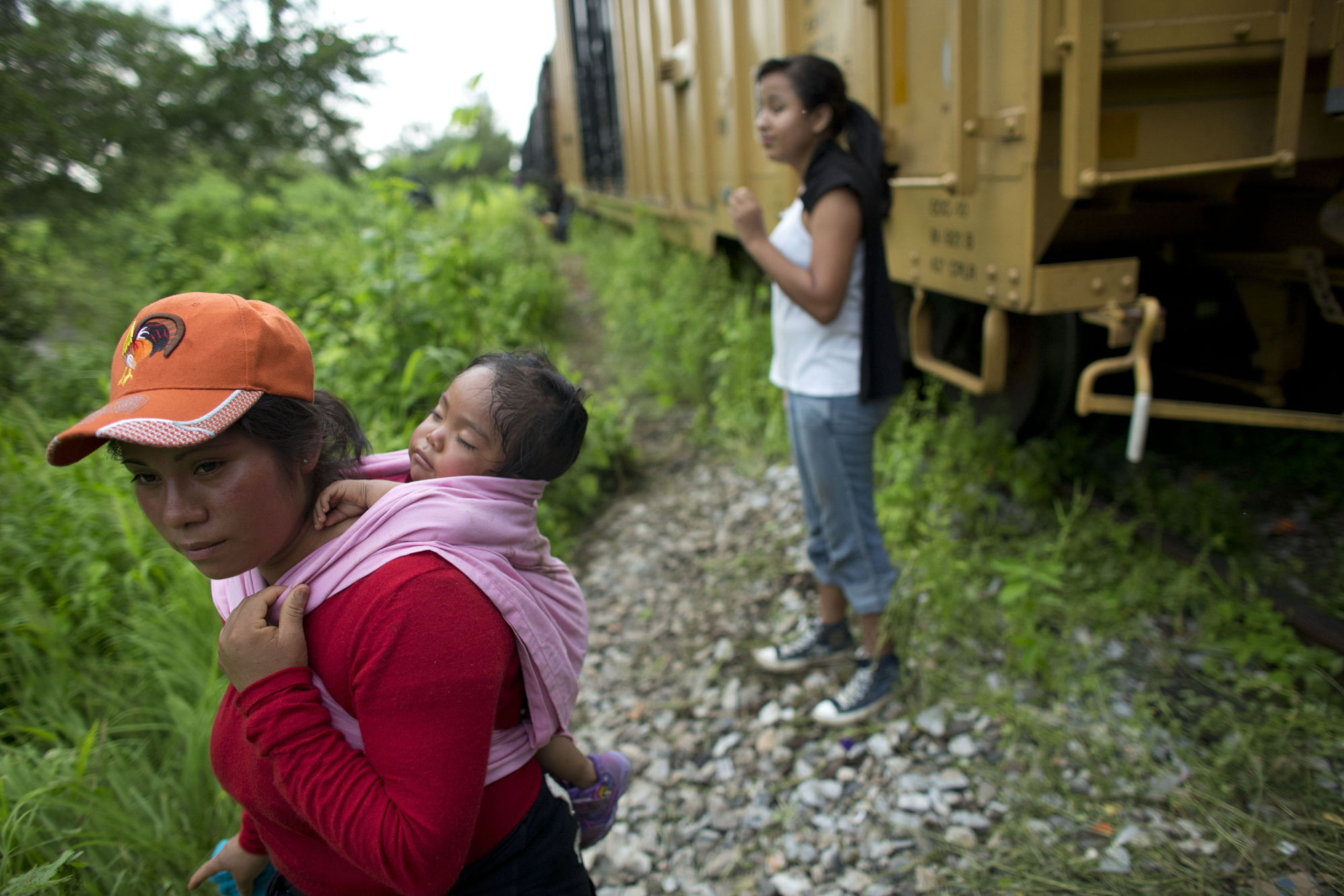 Guatemalan migrant Gladys Chinoy, 14, right, waits with more than 500 other migrants, many traveling with small children, beside the stuck freight train on which they were traveling, outside Reforma de Pineda, Mexico, June 20.