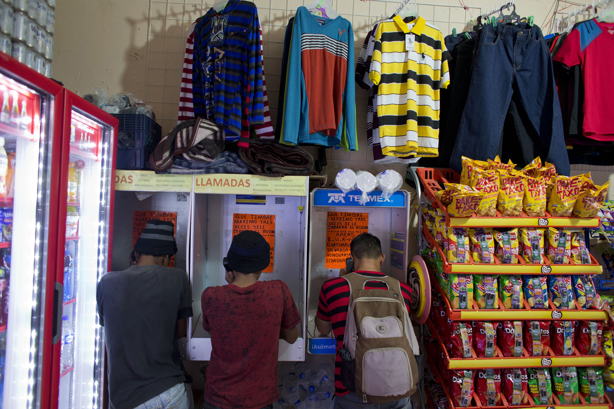 Central American migrants, including two 17-year-old Guatemalans, left, who were traveling with a smuggler, use pay phones to call their families as they wait for the arrival of a freight train to carry them north, in Arriaga, Mexico, June 18.