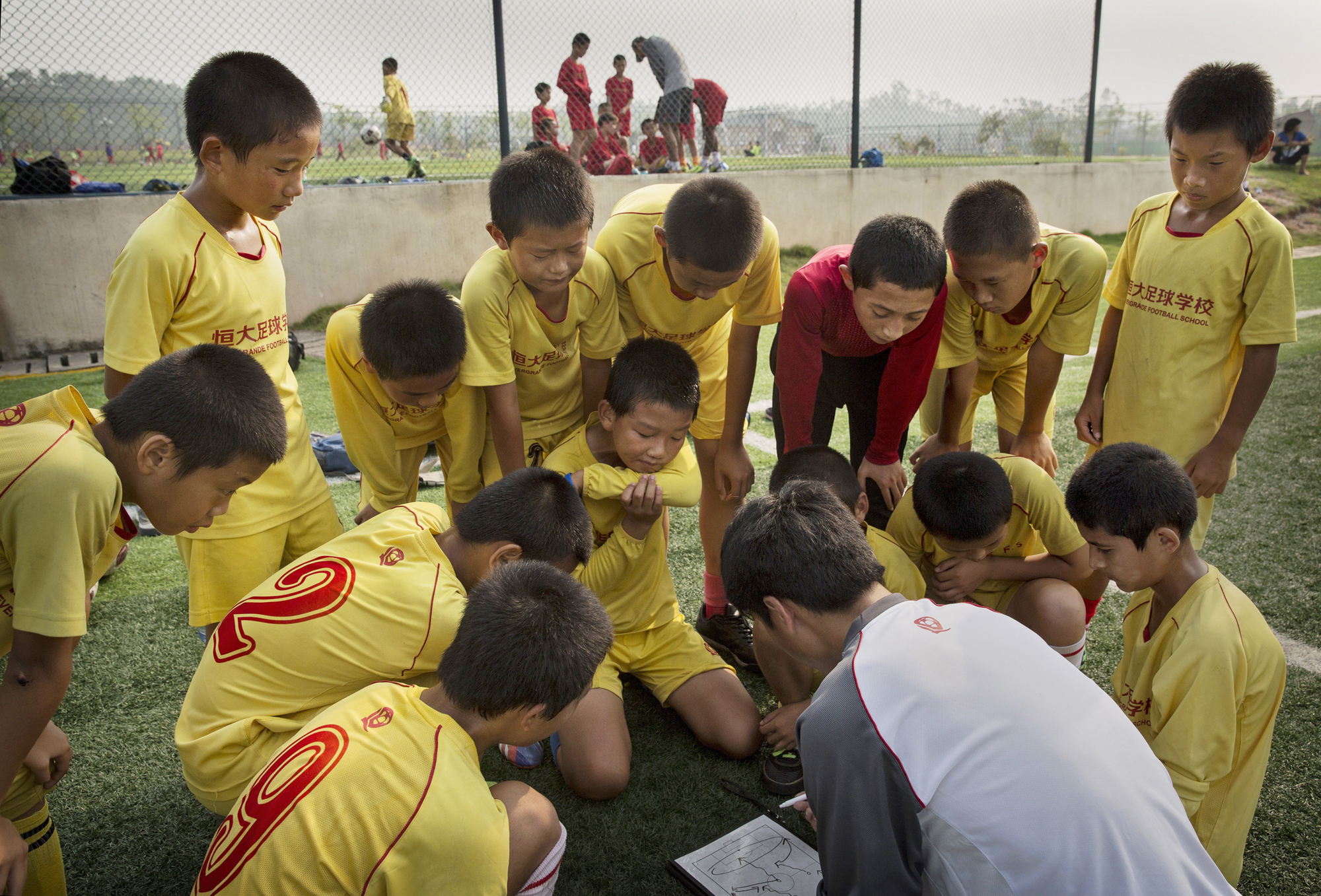 Players listen to instructions from the coach prior to a training match at the Evergrande International Football School on June 14.