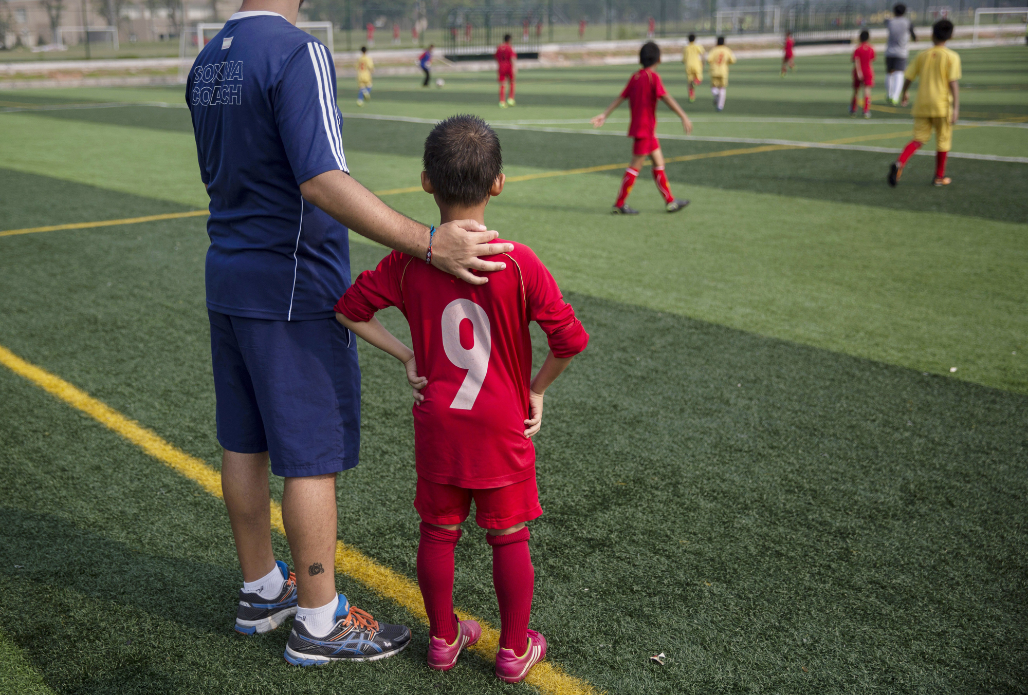 A coach from Real Madrid stands with a young Chinese student before subbing him to a training match at the Evergrande International Football School on June 14.