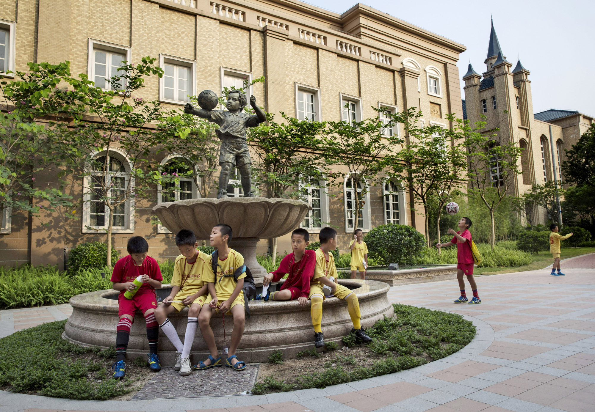 Young soccer players sit together in the campus as they wait to head to training at the Evergrande International Football School on June 14.