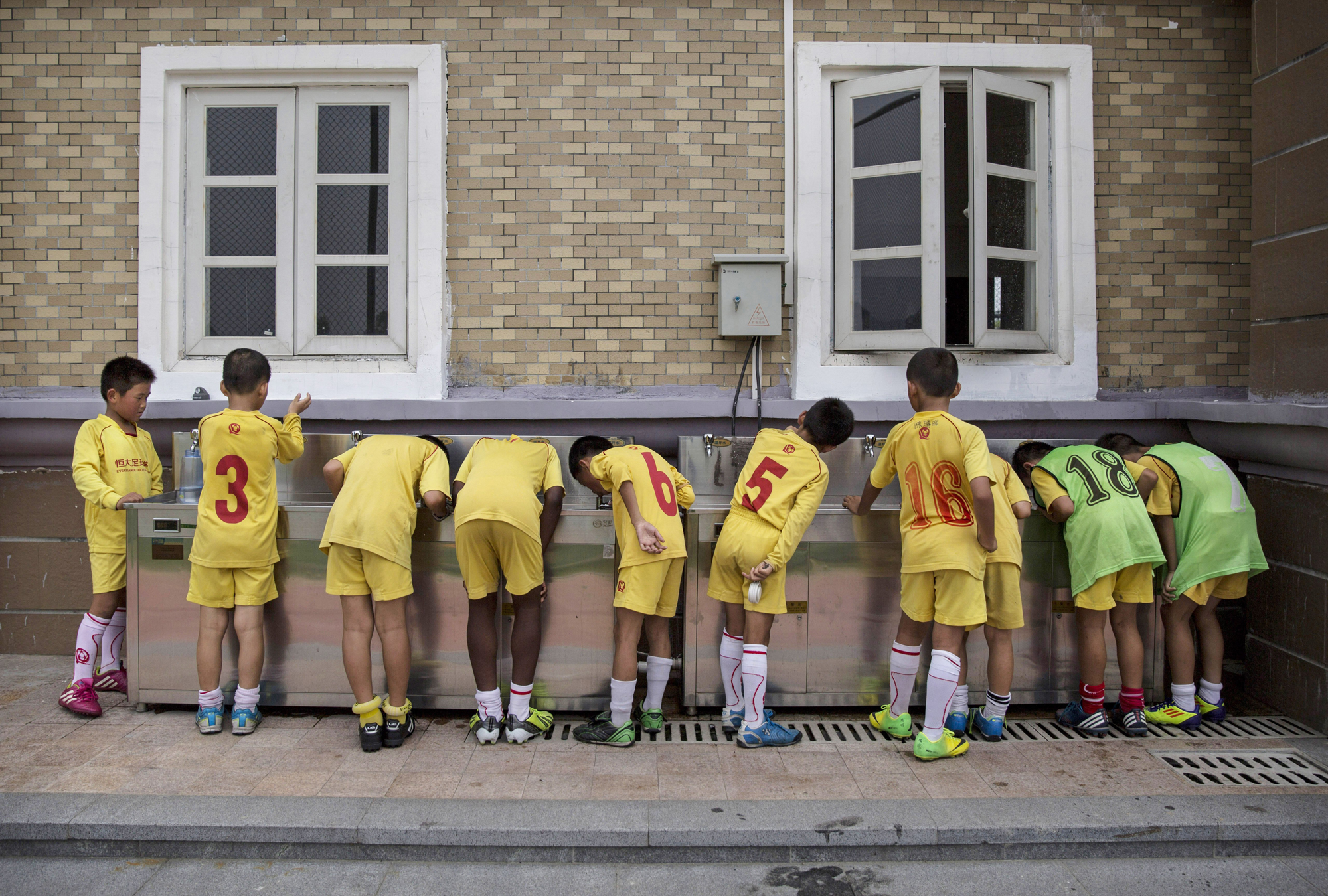 Players drink water from a communal tap after training at the Evergrande International Football School on June 12.