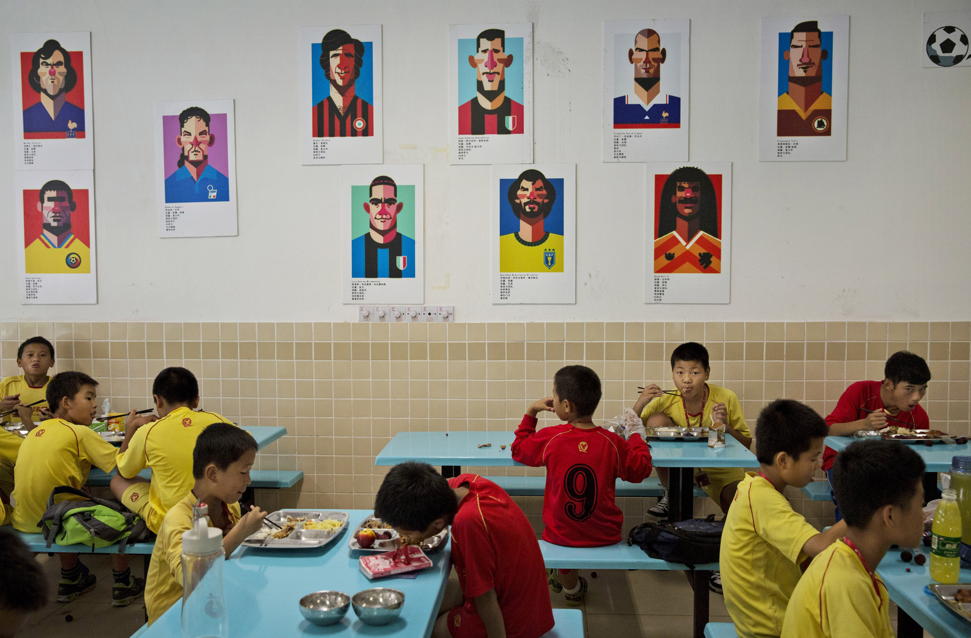 Players eat lunch under caricatures of famous soccer players in the canteen at the Evergrande International Football School on June 12.