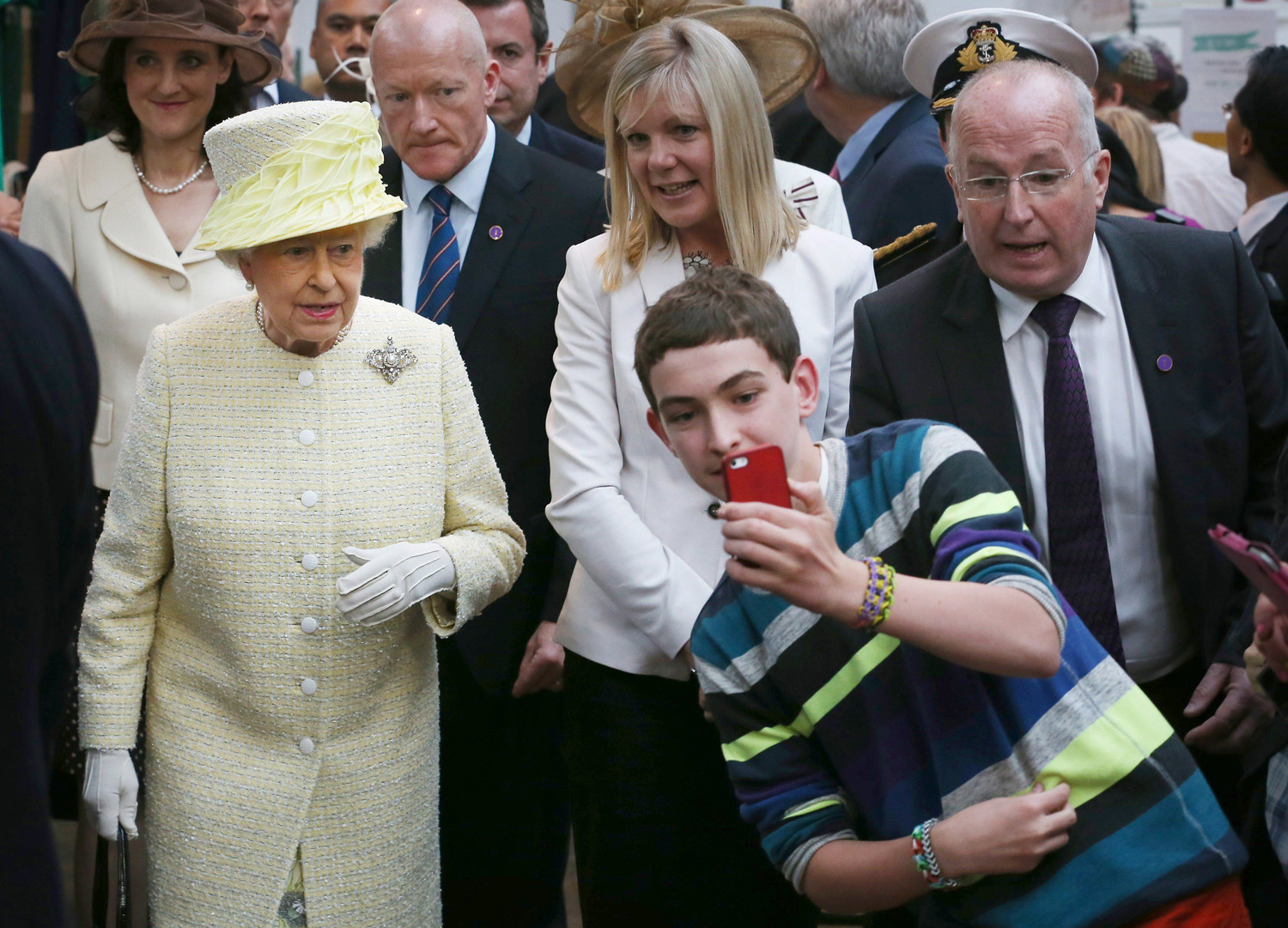 A local youth takes a selfie in front of Queen Elizabeth II during a visit to St George's indoor market in Belfast, Northern Ireland on June 24, 2014.