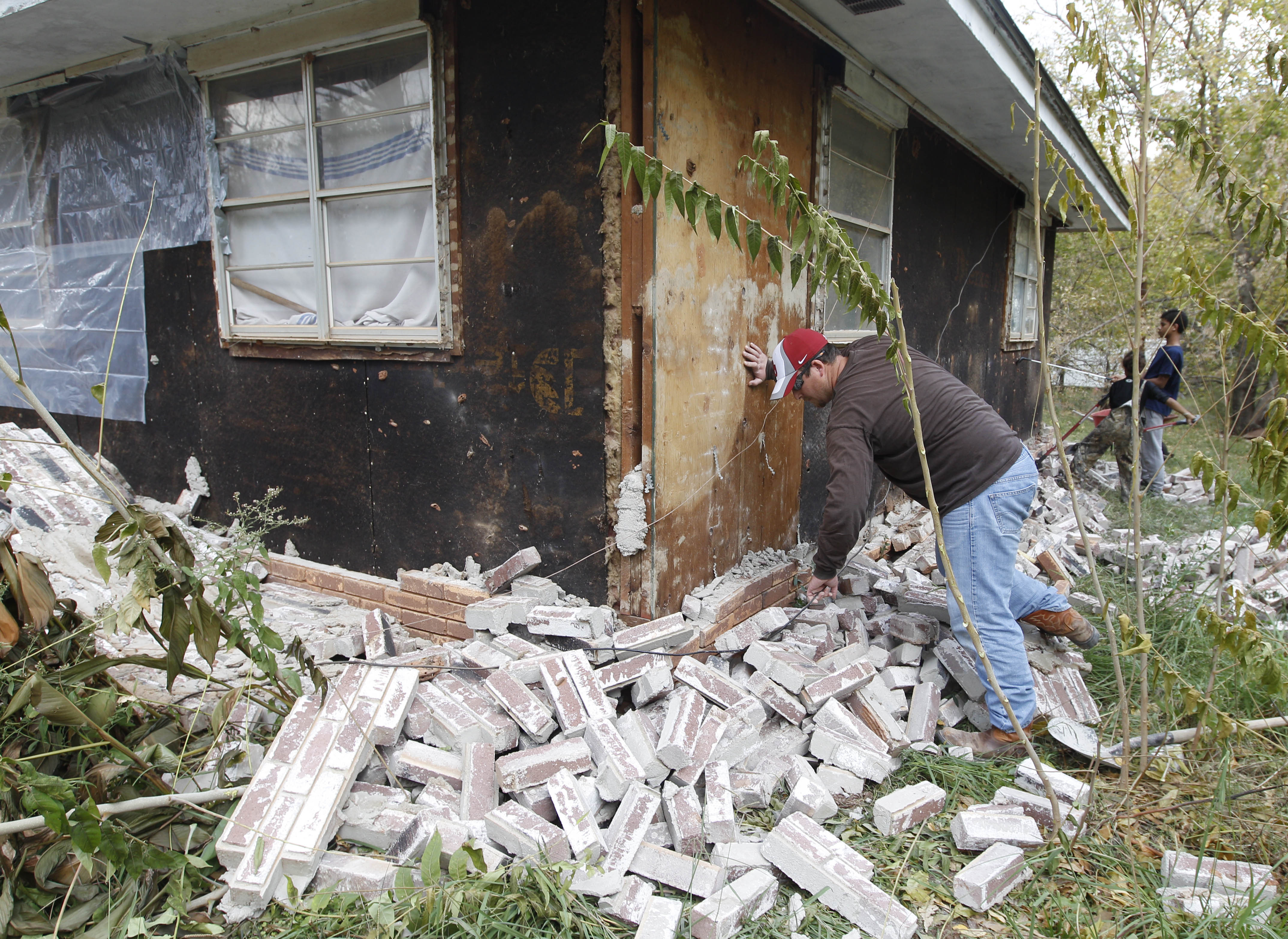 Chad Devereaux examines bricks that fell from three sides of his in-laws' home in Sparks, Okla., on Nov. 6, 2011, following two earthquakes that hit the area. (Sue Ogrocki—AP)