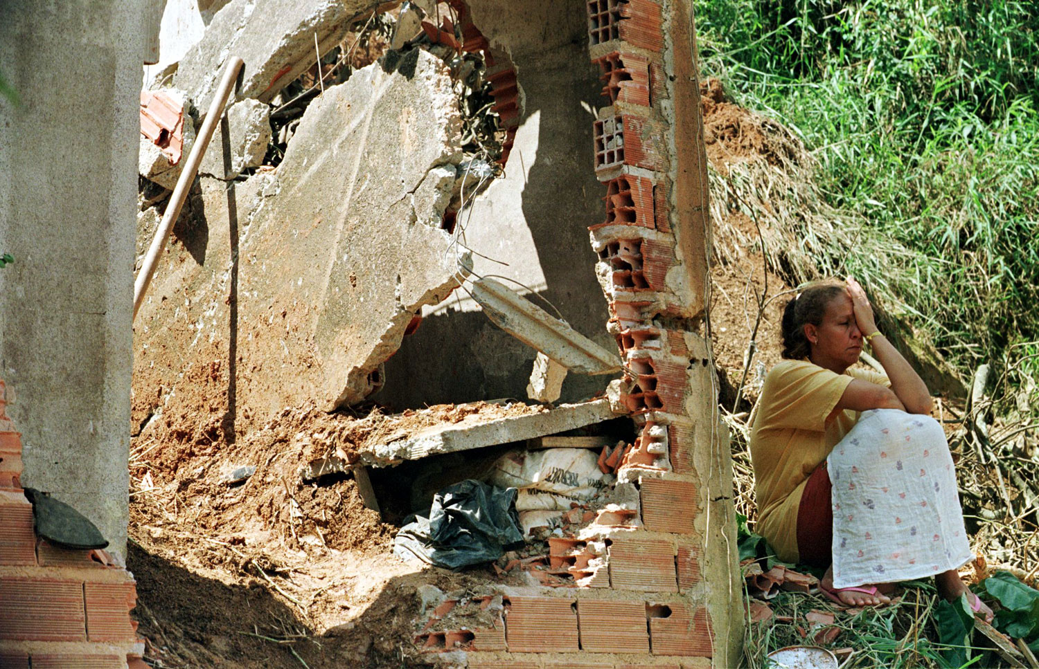 A resident  grieves while sitting by the ruins of her neighbor' house s on March 3, 1999 after it collapsed killing one person during a landslide triggered by recent torrential rains. Some 28 people have died in Sao Paulo since the beginning of 1999 as a direct consequence of the disastrous weather caused by the weather phenomenon known as  La Nina.