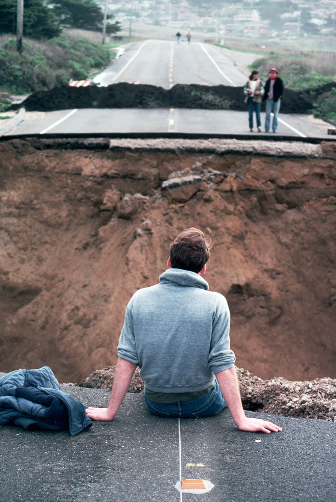 Man Sitting on Washed Out Road