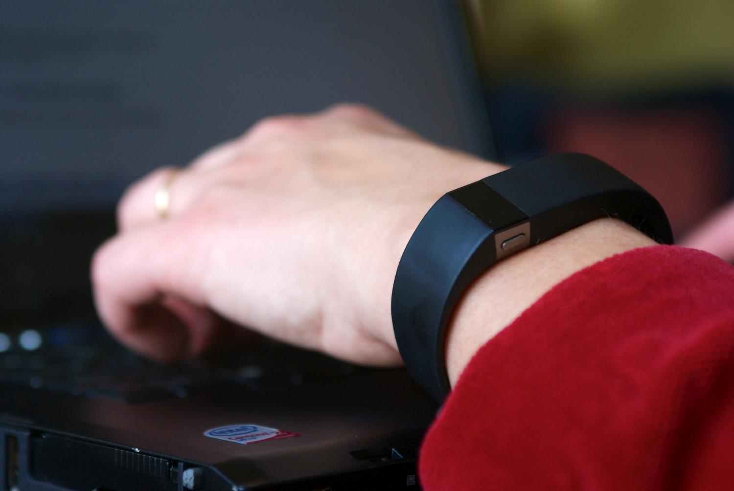 A person wearing a Fitbit fitness band types on a laptop (Getty Images)