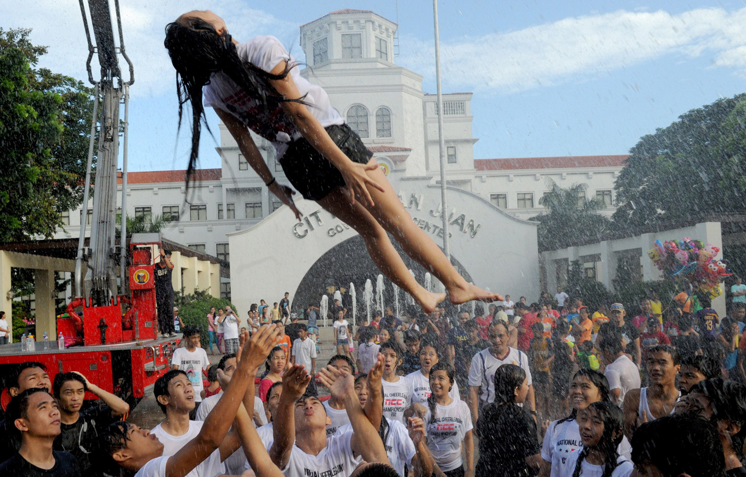 A woman is hoisted into the air by friends after they were sprayed with water as residents celebrate the feast day of St. John the Baptist in Manila on June 24, 2014.