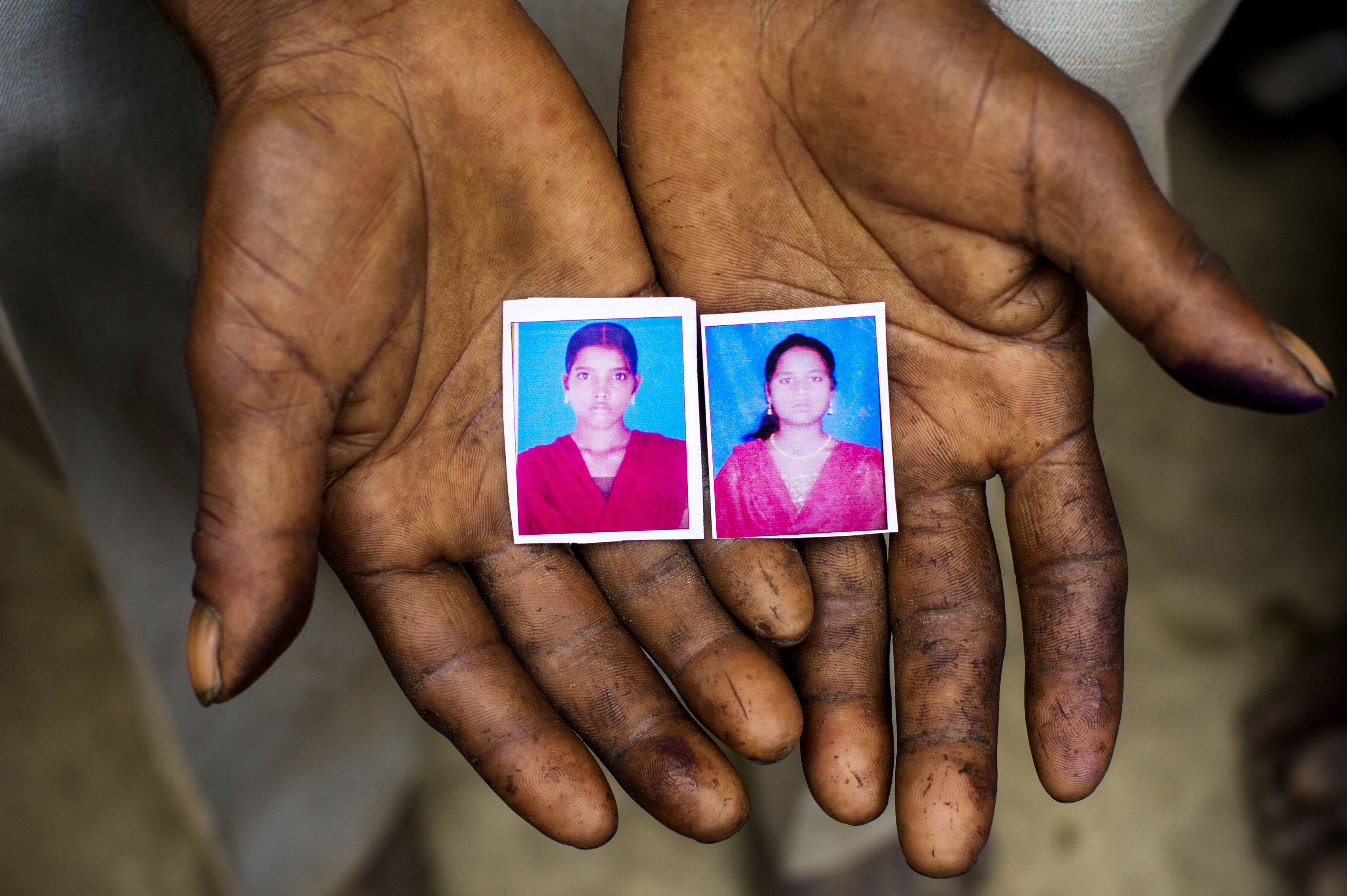 Sohan Lal (55) holds passport sized images in his hands of his daughter Murti (right) and niece Pushpa (left) in Katra Sadatganj village, Uttar Pradesh, India on May 30, 2014.