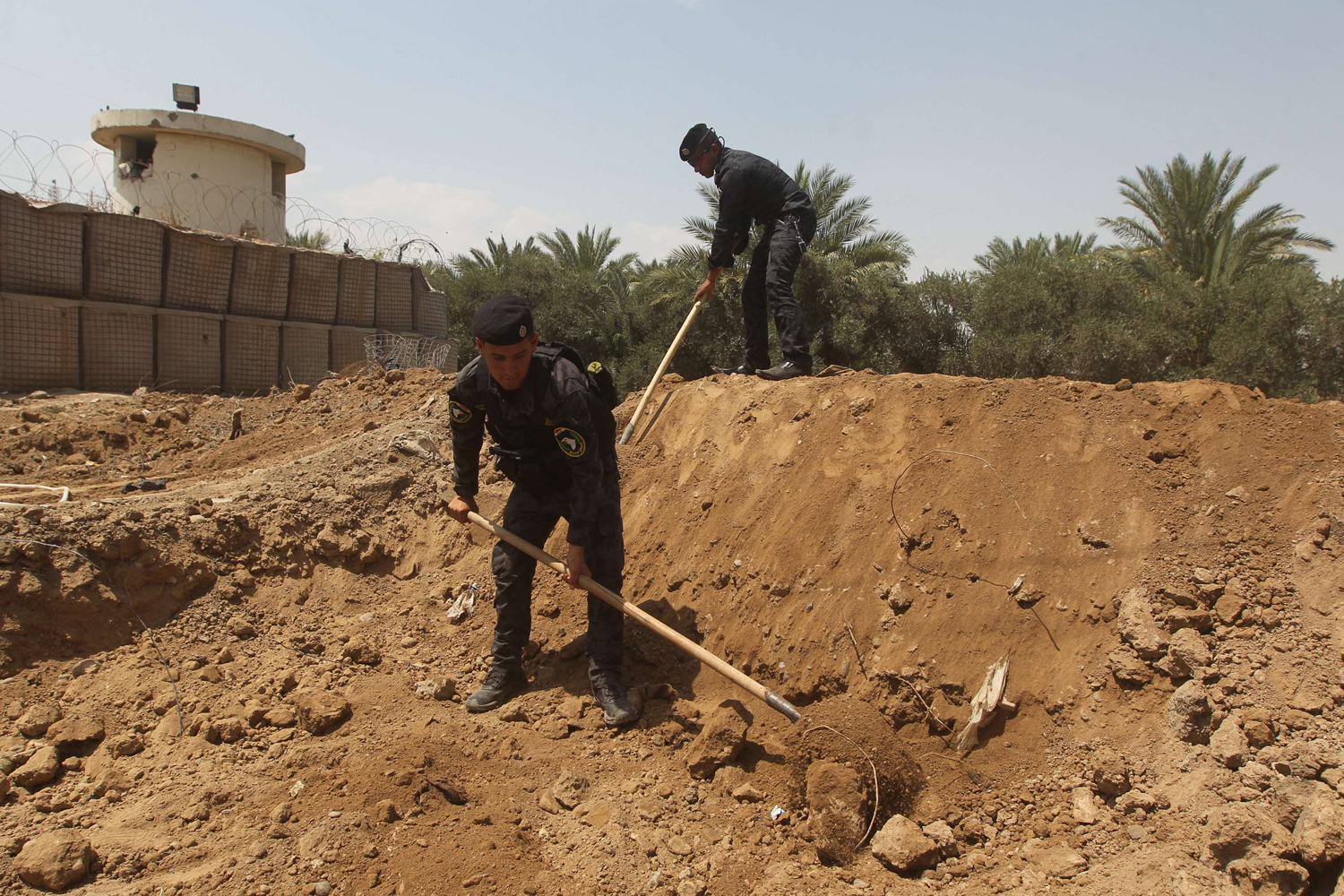 Iraqi policemen dig trenches at checkpoint in the Iraqi town of Taji, at the entrance of Baghdad, on June 13, 2014, as security forces are bolstering defenses in the capital.