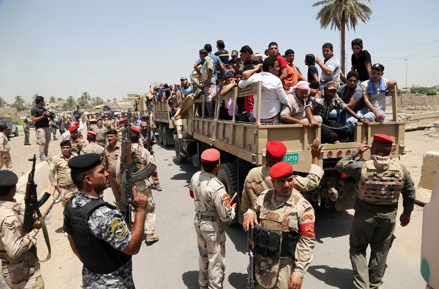 Iraqi men board military trucks to join the Iraqi army at the main recruiting center in Baghdad on June 14, after authorities urged Iraqis to help battle insurgents.