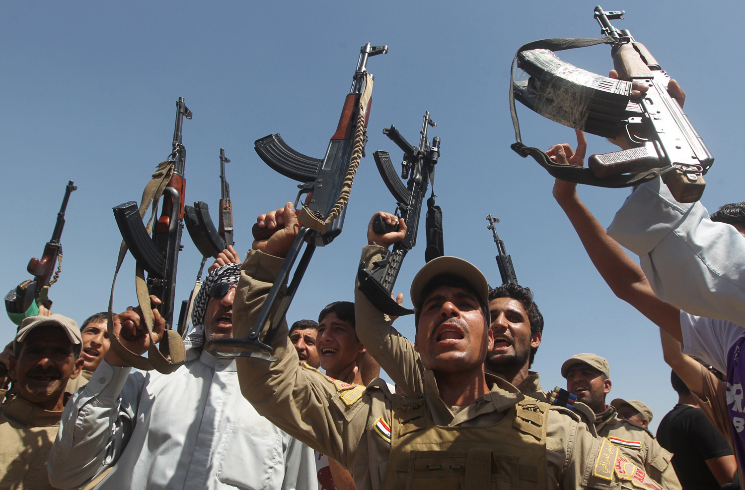 Shiite men, some of them wearing military fatigues and guns given by the government, raise their weapons as they gather in the Iraqi town of Jdaideh in the Diyala province on June 14, to show their support for the call to arms by Shiite cleric Grand Ayatollah Ali al-Sistani.
