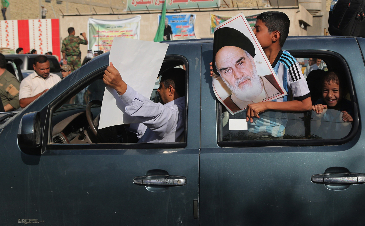 People hold posters showing Iran's spiritual leaders Ayatollah Khomeini, while Iraqi Shiite fighters deploy with their weapons in Basra, Iraq's second-largest city, 340 southeast of Baghdad, June 14.