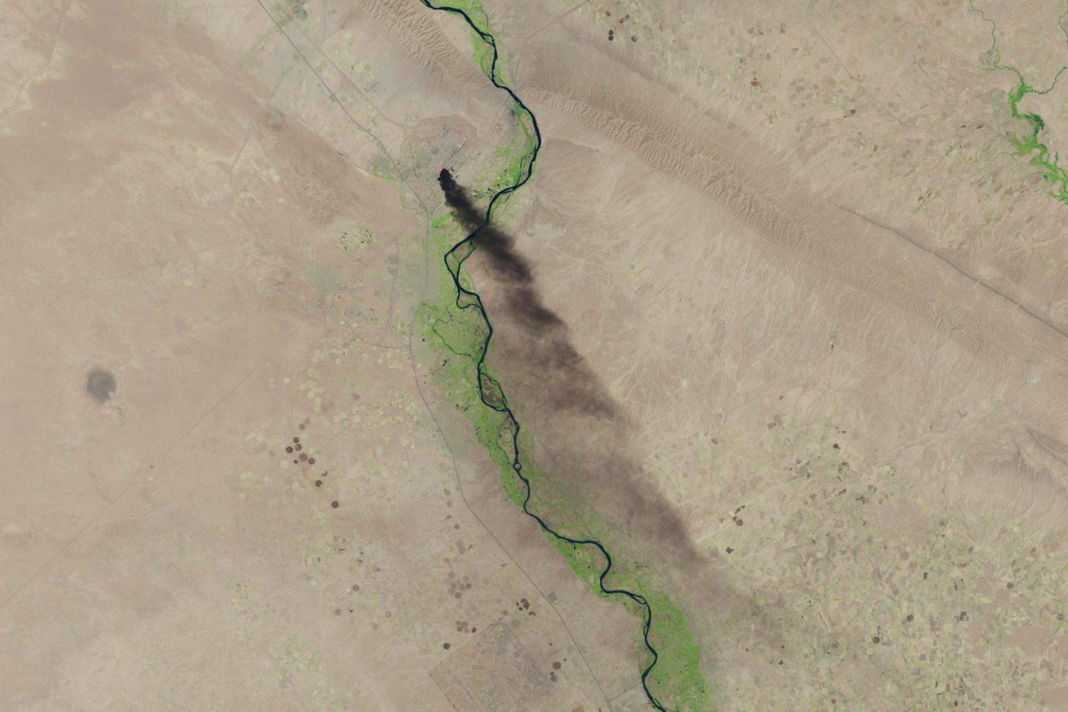 A satellite image shows smoke rising from the Baiji refinery near Tikrit, Iraq, June 18. (U.S. Geological Survey/Reuters)