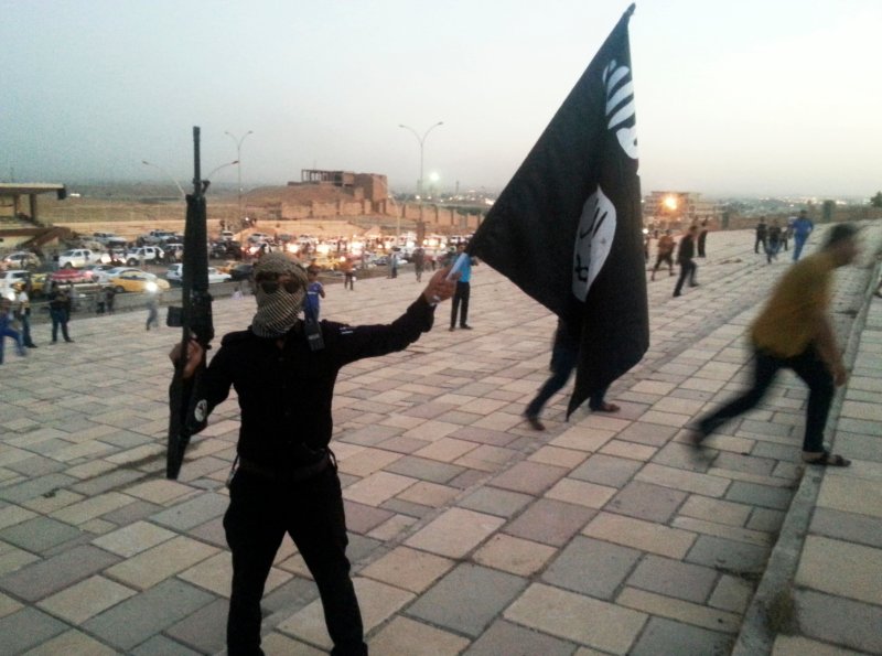 A fighter of the Islamic State of Iraq and Greater Syria (ISIS) holds an ISIS flag and a weapon on a street in the city of Mosul, Iraq, on June 23, 2014