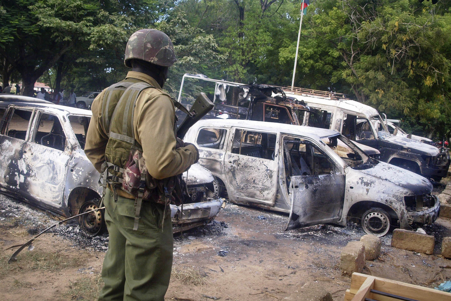 A member of the Kenyan security forces observes the remains of vehicles destroyed by militants, in the village of Kibaoni just outside the town of Mpeketoni, about 60 miles from the Somali border on the coast of Kenya, June 16, 2014.