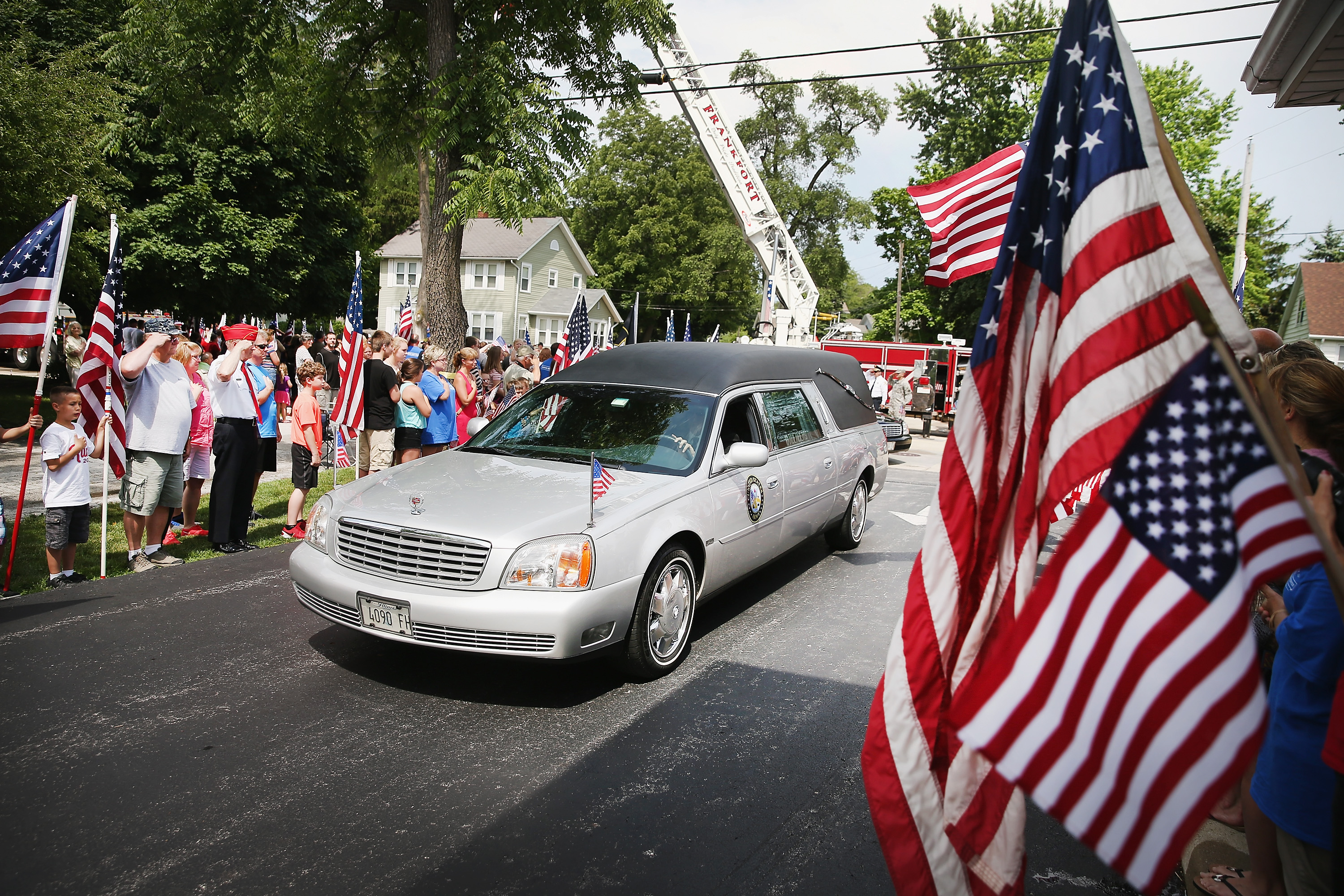 Supporters watch as the remains of Army Pfc. Aaron Toppen arrive at the funeral home on June 21, 2014 in Mokena, Ill.