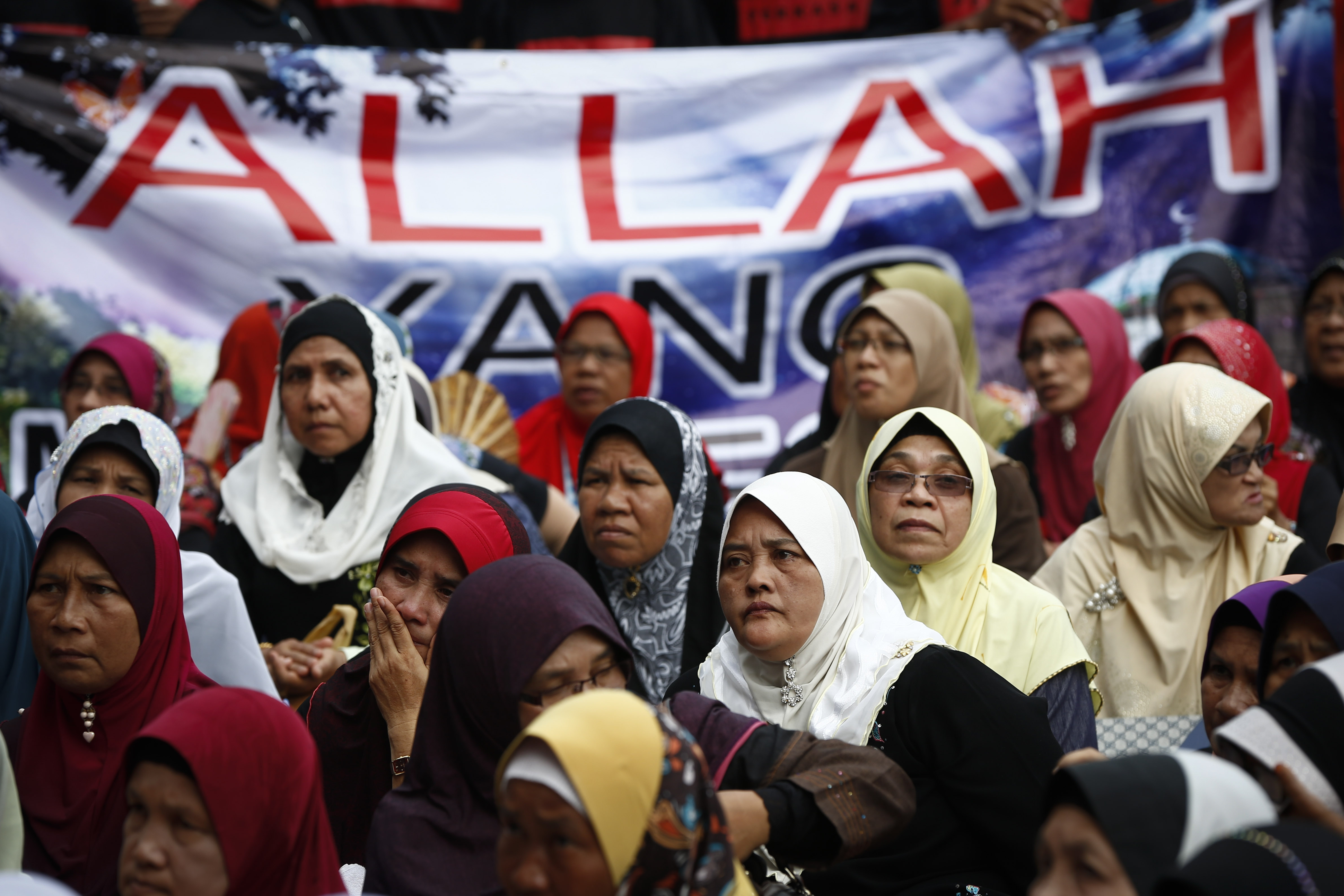 Muslim women sit in front of a banner reading <i>Allah</i> during a protest outside the court of appeal in Putrajaya, outside Kuala Lumpur, on June 23, 2014 (Vincent Thian—AP Photo)