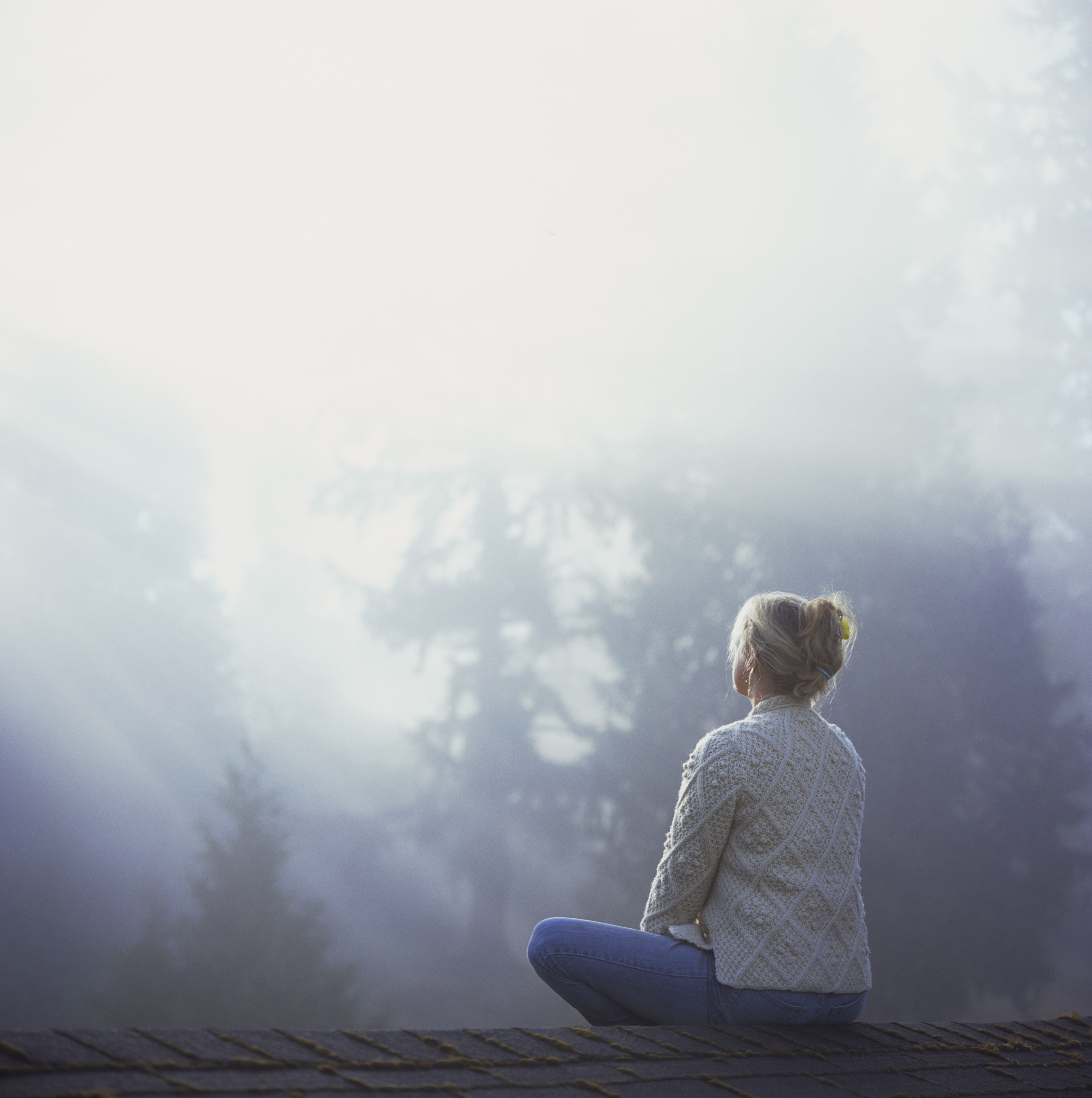 Woman meditating near Douglas fir trees (Aaron McCoy—Getty Images)