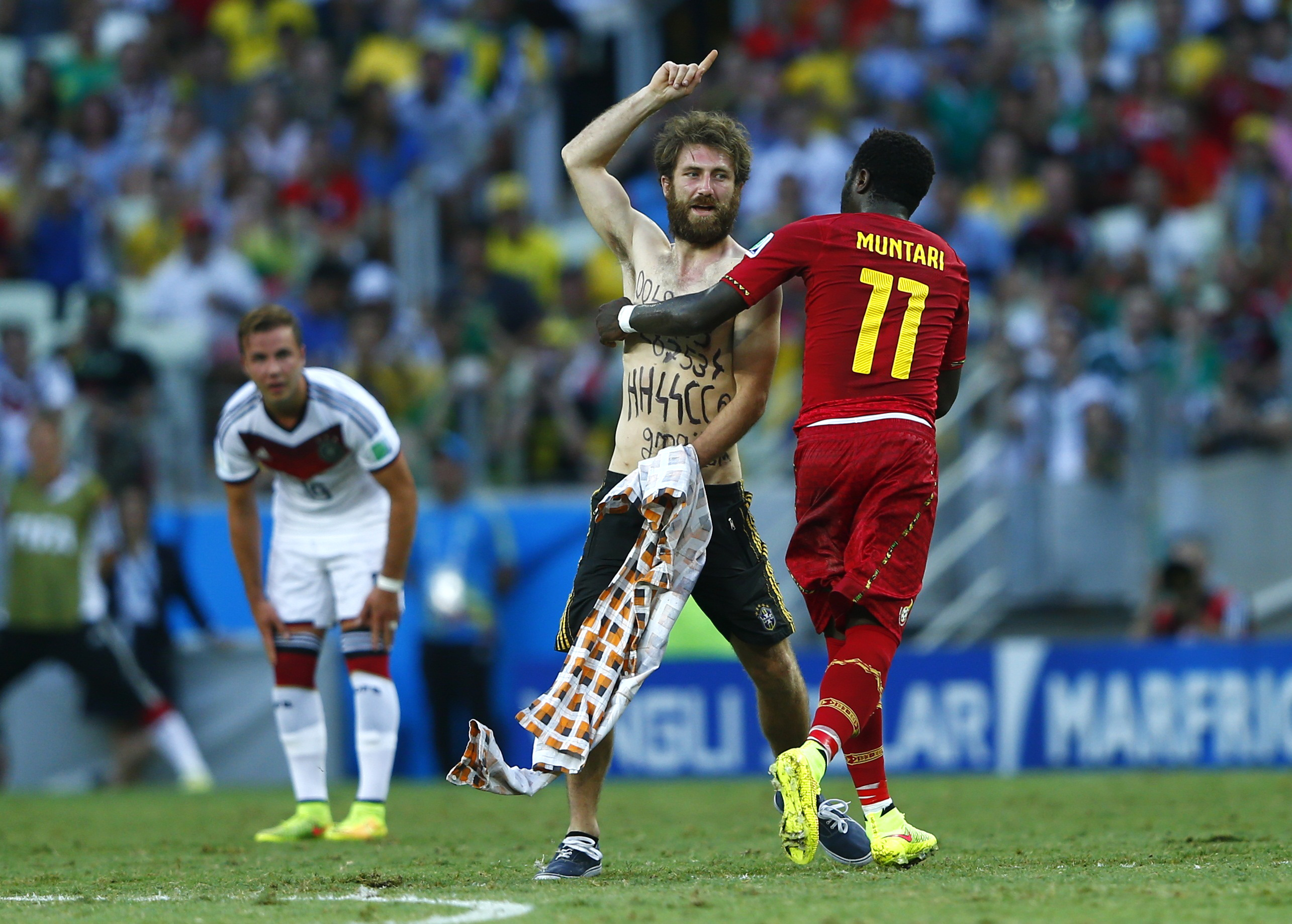 Ghana's Sulley Muntari helps a spectator off the field during the 2014 World Cup soccer match between Germany and Ghana on June 21, 2014. (Eddie Keogh/Reuters)