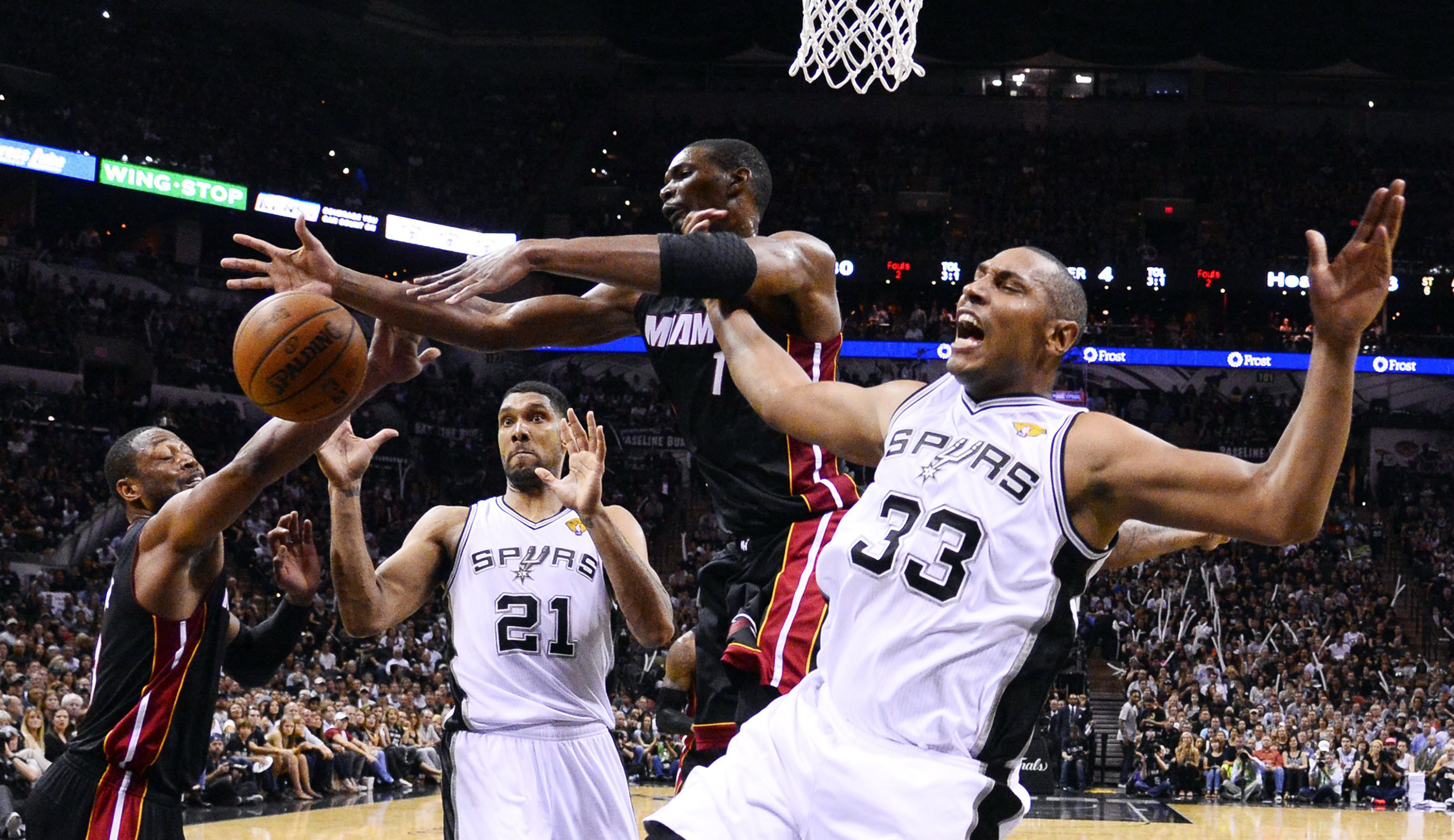 San Antonio Spurs player Boris Diaw (R) passes the ball to Tim Duncan (L) against Miami Heat player Chris Bosh (C) in the second half of the NBA Finals Game 2 in San Antonio on June 8, 2014.