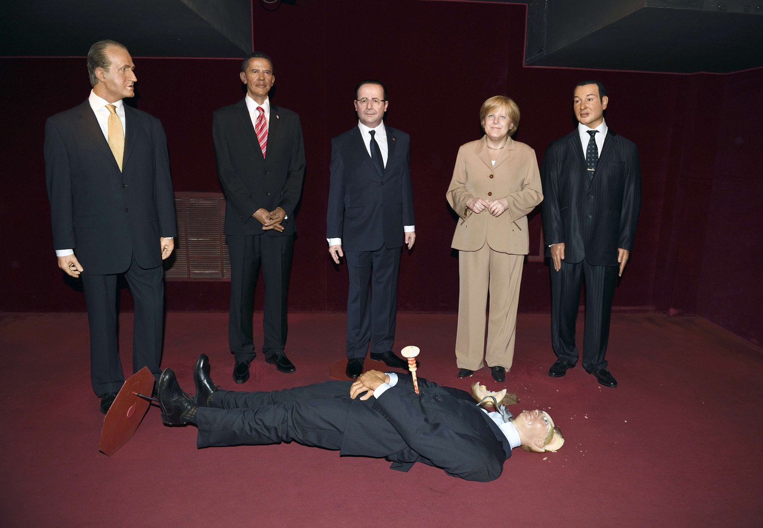 The wax statue representing Russian President Valadimir Putin whose head was damaged by an activist of the Femen feminist group lies on the floor next to wax statues of Spain's King Juan Carlos (L) US President Barack Obama (2ndL), French President Francois Hollande (C), German Cancellor Angela Merkel (2ndR) and Morocco's King Mohamed VI (R) at the Grevin museum in Paris on June 5, 2014.