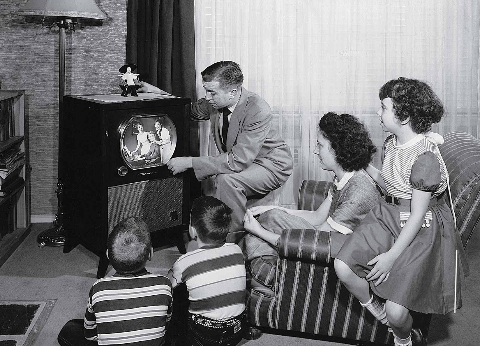 Parents with three children watching television