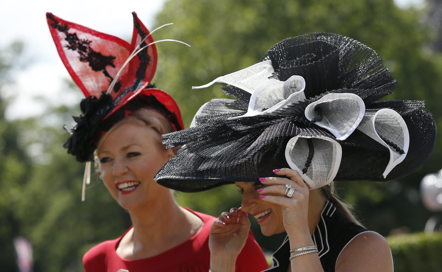 Race goers hang onto their hats in a gusty wind as they arrive on the first day of the Royal Ascot horse racing meeting at Ascot, England, June, 17, 2014.