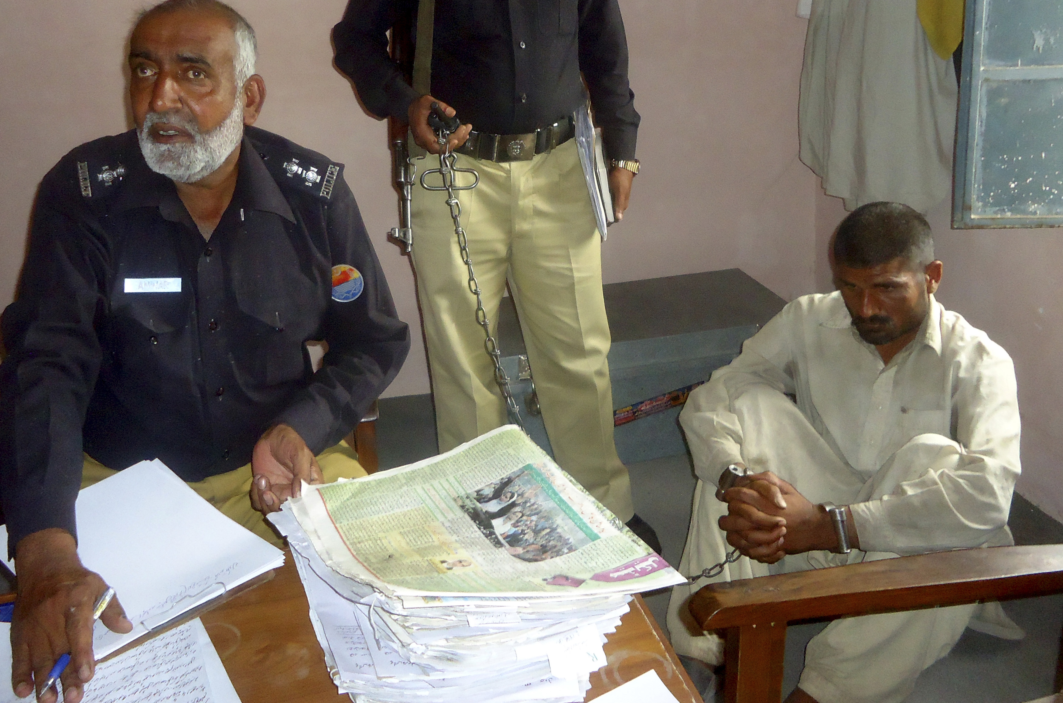 Mohammad Arif Ali, 35, right, sits in custody at a police station in the town of Darya Khan in Bhakkar district, Pakistan's Punjab province, on April 14, 2014. (Reuters)