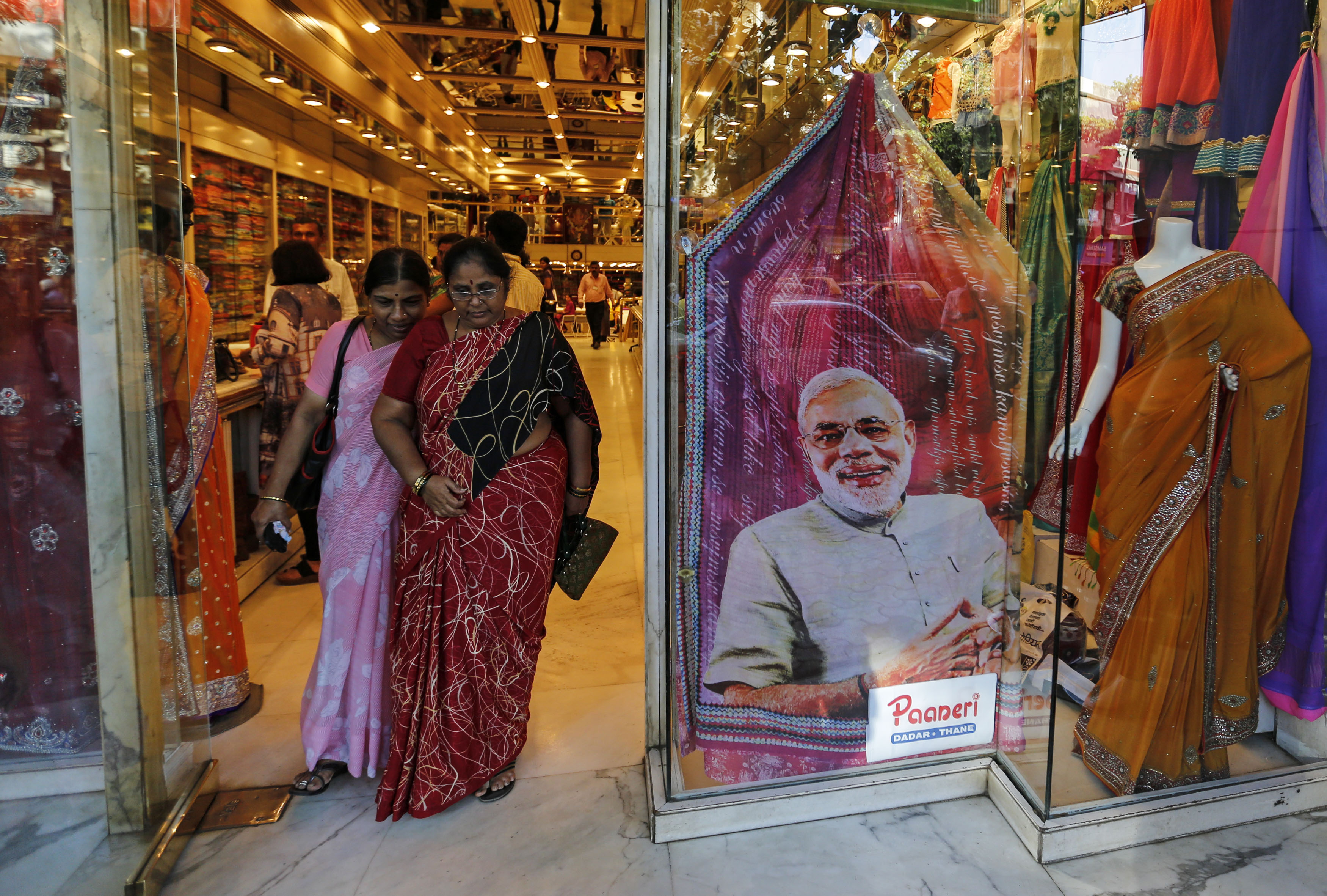 Customers walks past a sari, a traditional women's clothing, printed with a portrait of Hindu nationalist Narendra Modi, the prime ministerial candidate for India's main opposition Bharatiya Janata Party (BJP), at a showroom in Mumbai