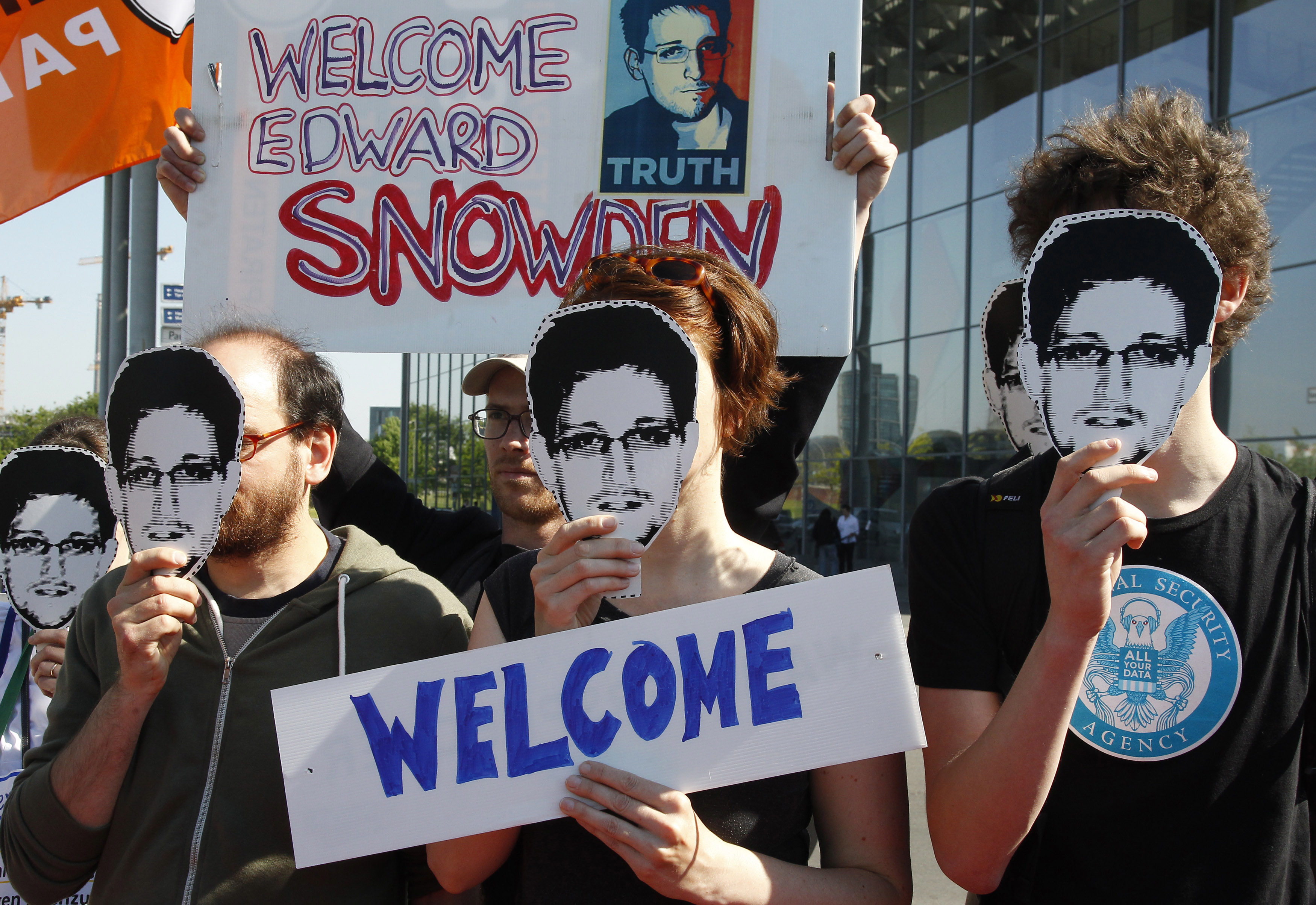 Protesters hold masks depicting Snowden during demonstration in Berlin