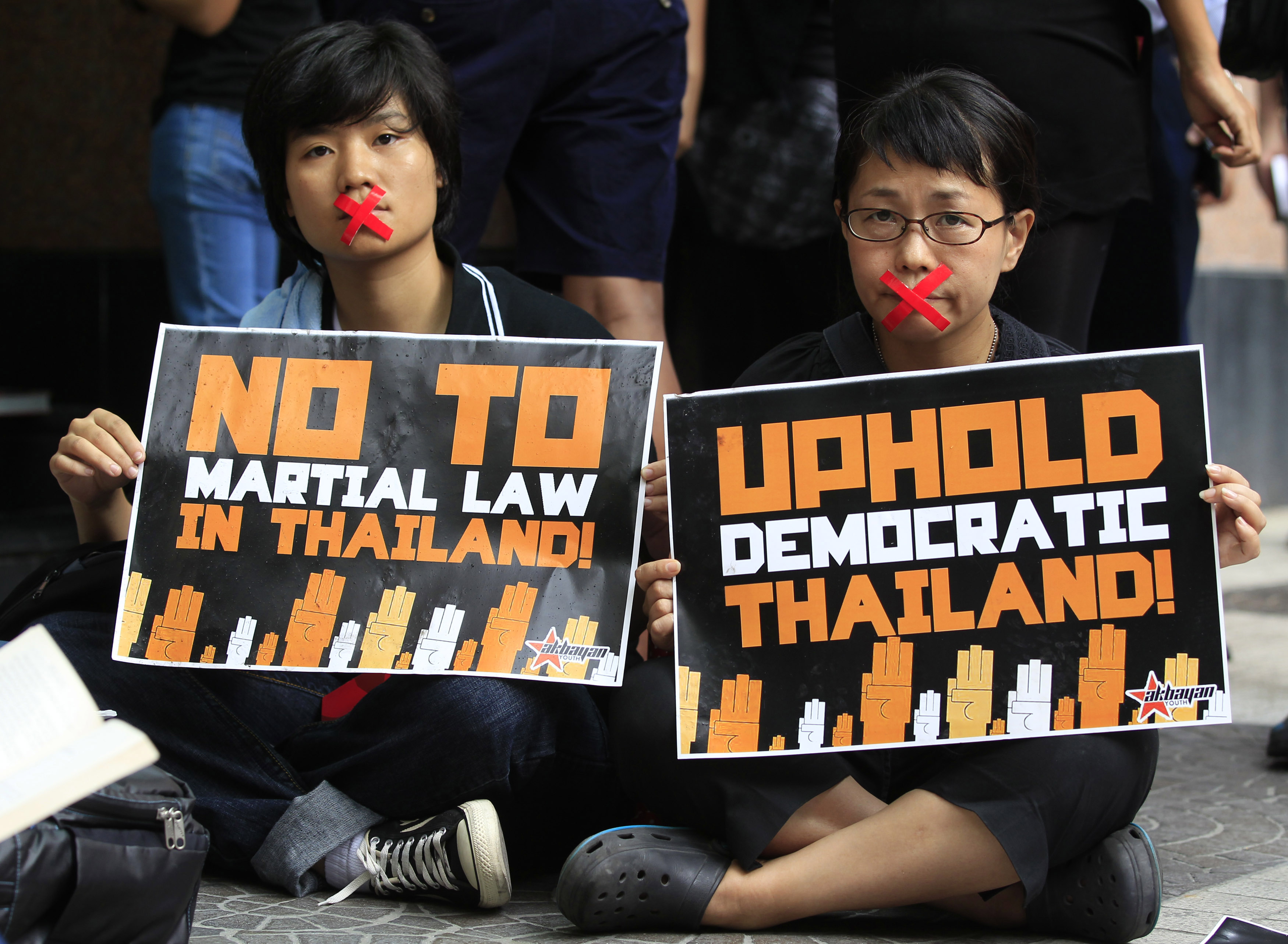 Activists, with their mouths taped up as a form of protest against the ongoing military rule in Thailand, hold placards during a picket in front of the Thai embassy in Manila