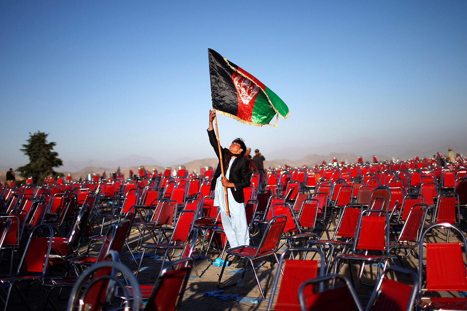 Supporter of Afghan presidential candidate Abdullah Abdullah holds an Afghan flag after an election campaign rally in Paghman district of Kabul