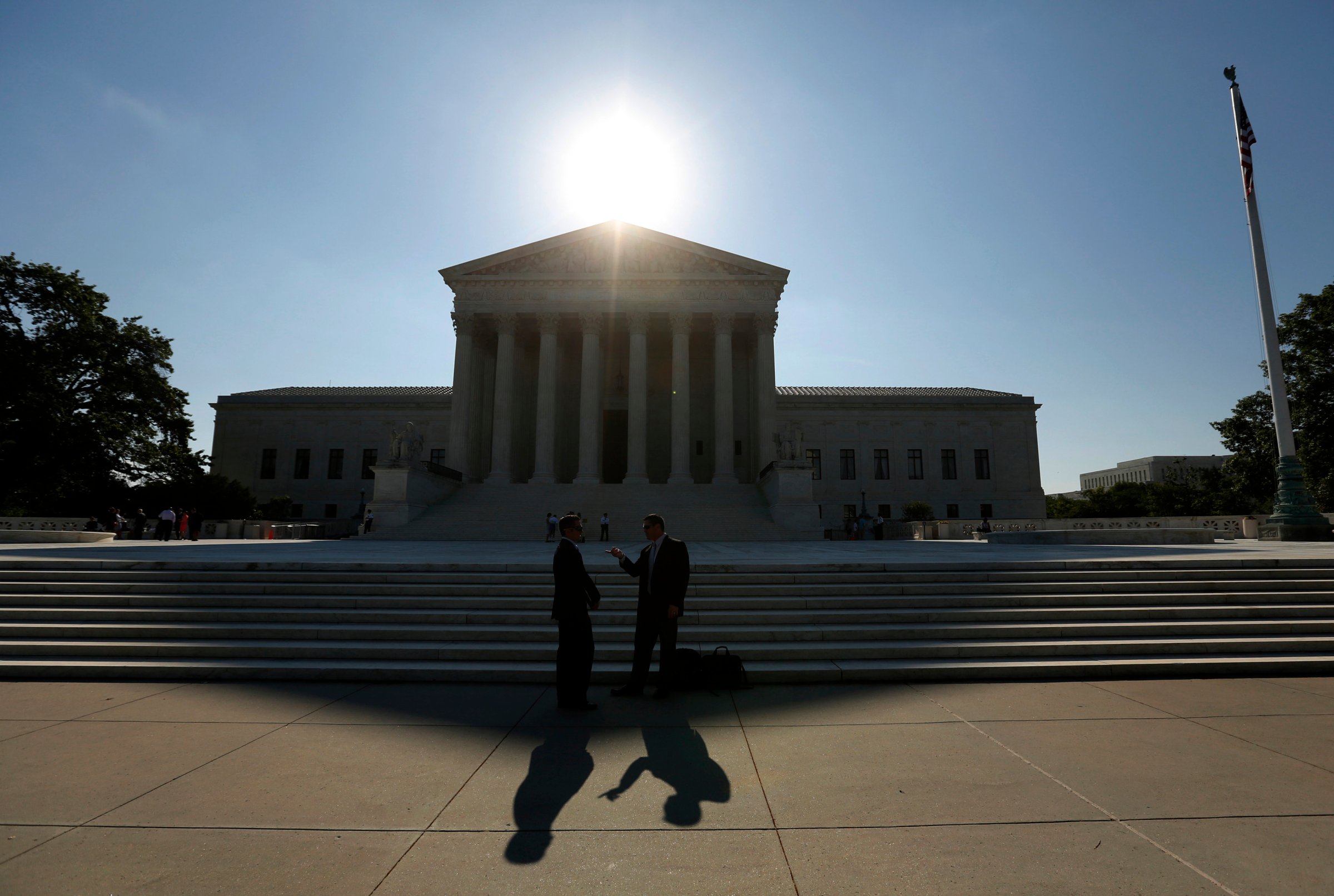 Two men talk as the sun rises over the Supreme Court in Washington