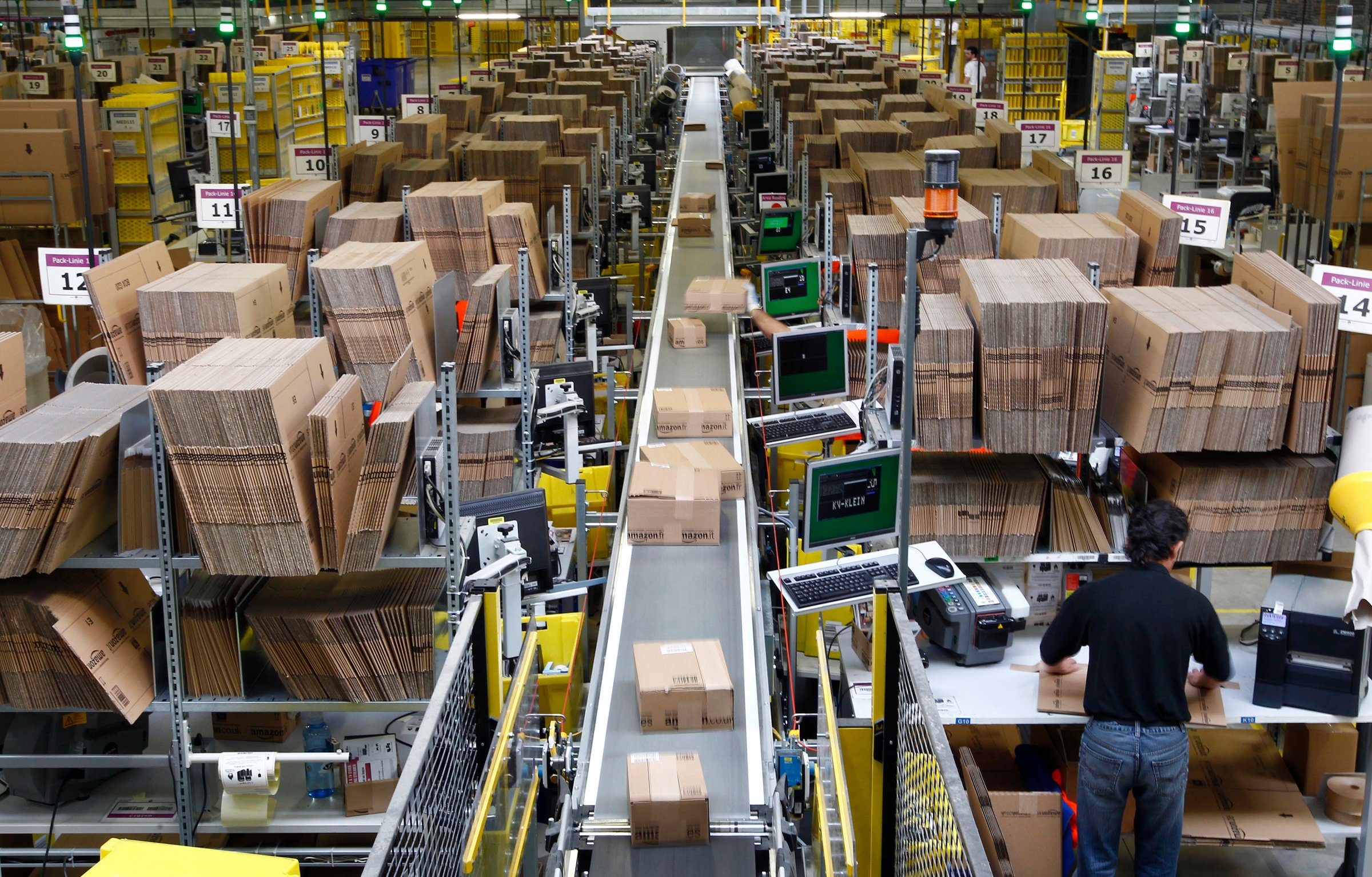 Workers pack boxes at Amazon's logistics centre in Graben